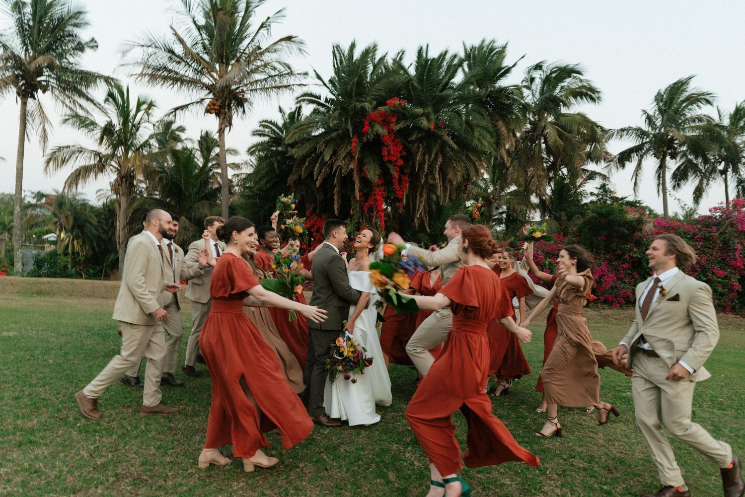 A wedding party poses together wearing light blue dresses and khaki pants in an outdoor setting.