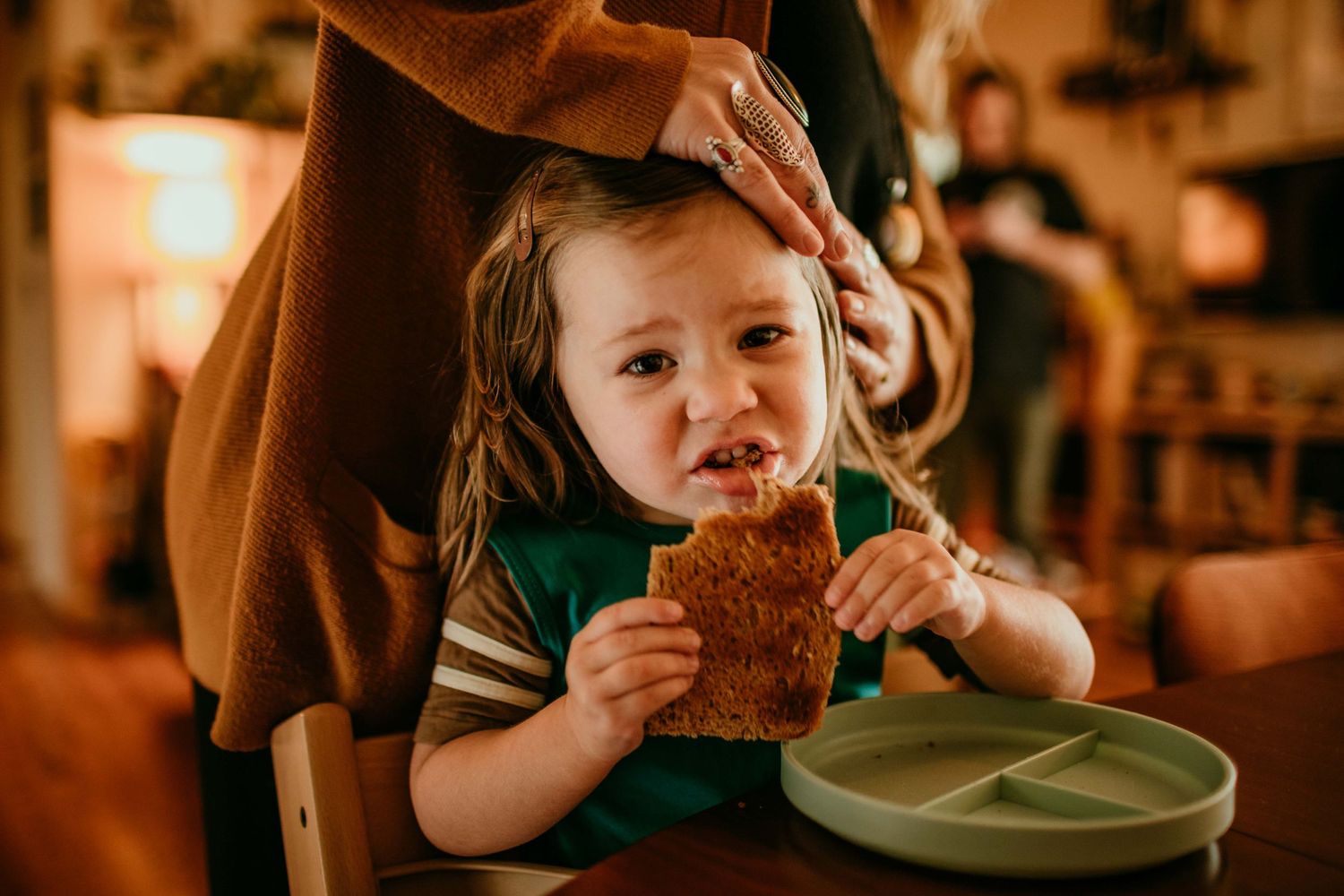 mom puts clip in child's hair during snack time portland oregon family photographer kimberly marie kimble