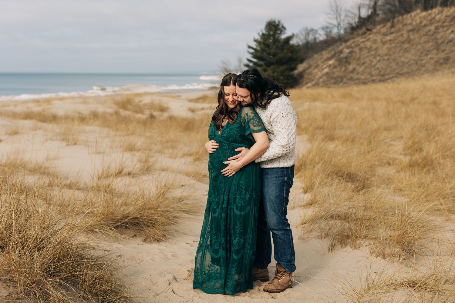 Romantic moment between couple in dressy attire on beach dunes.