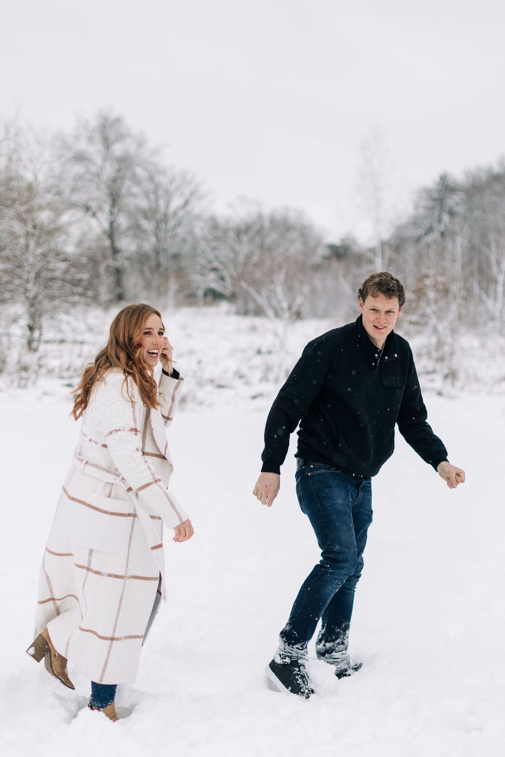 A couple enjoying a carefree moment while walking through snow-covered ground.