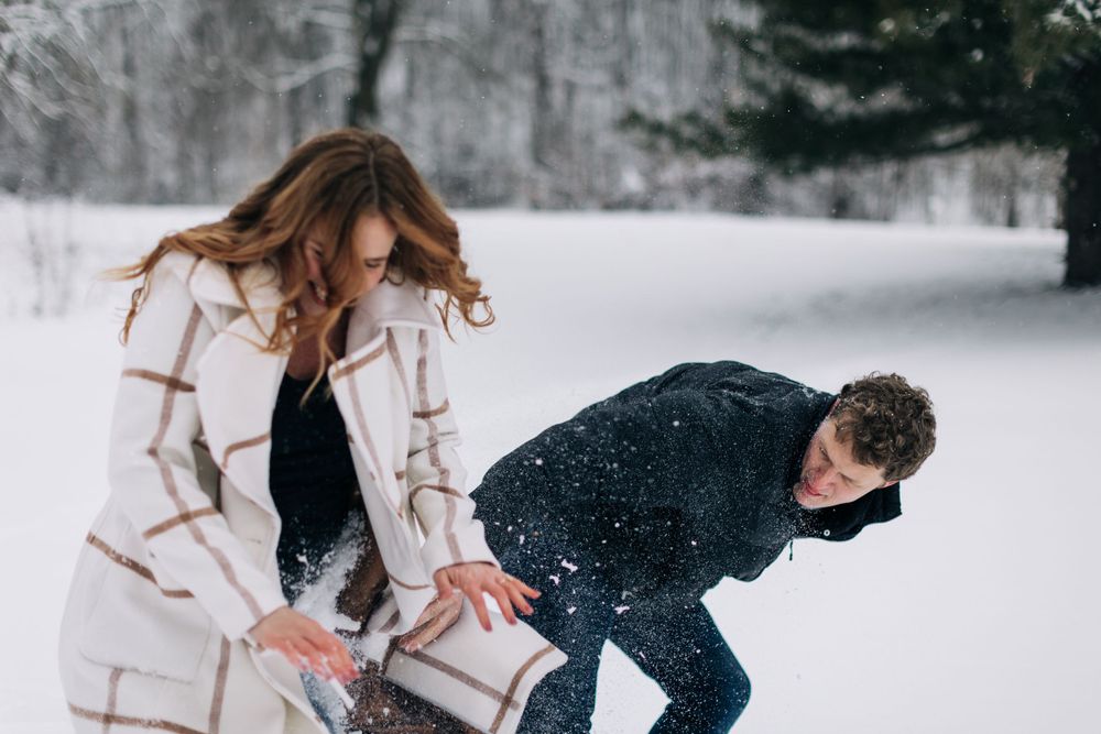 A playful winter scene with two people enjoying themselves in the snow.
