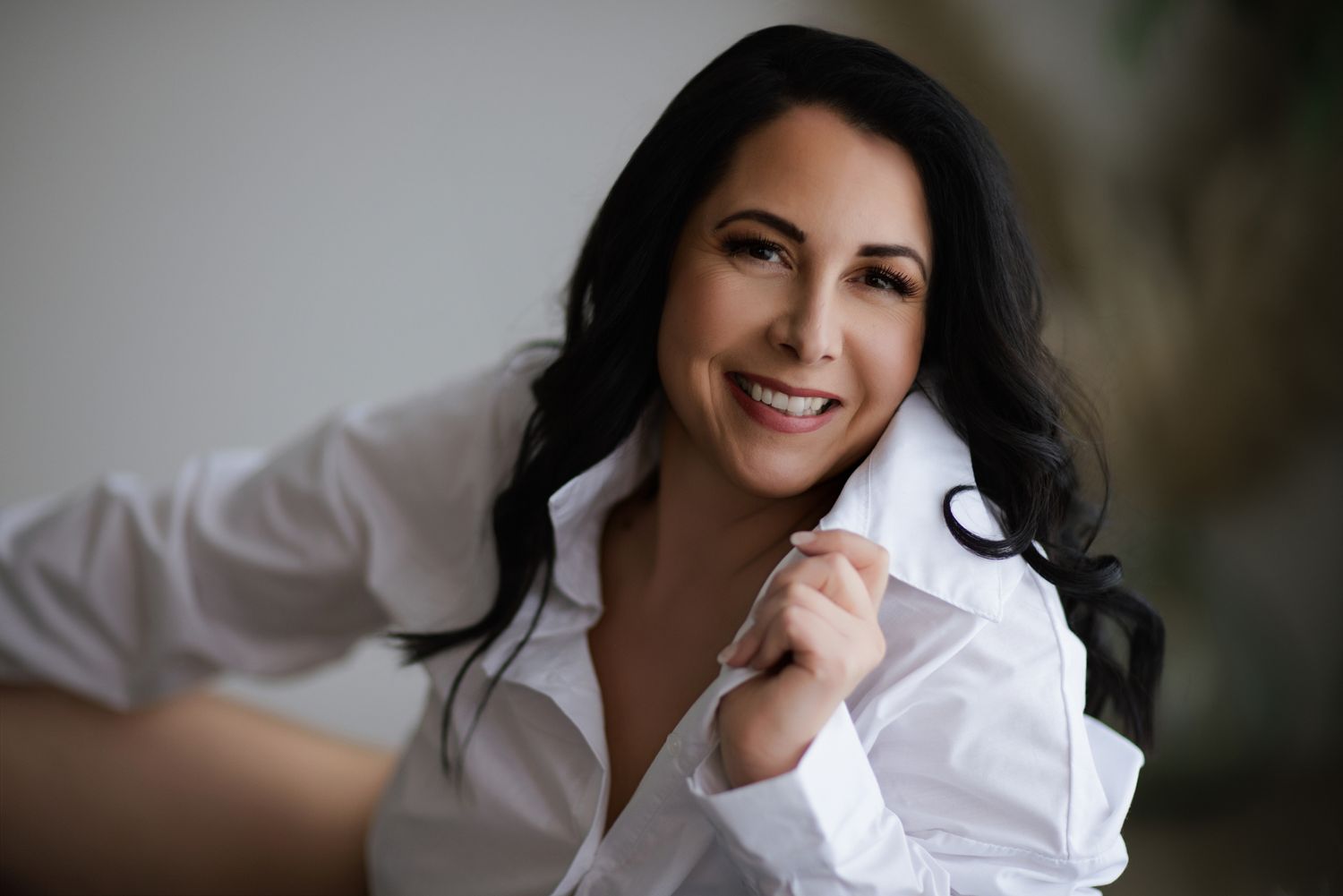 Professional headshot against blurred background showing warm genuine smile.