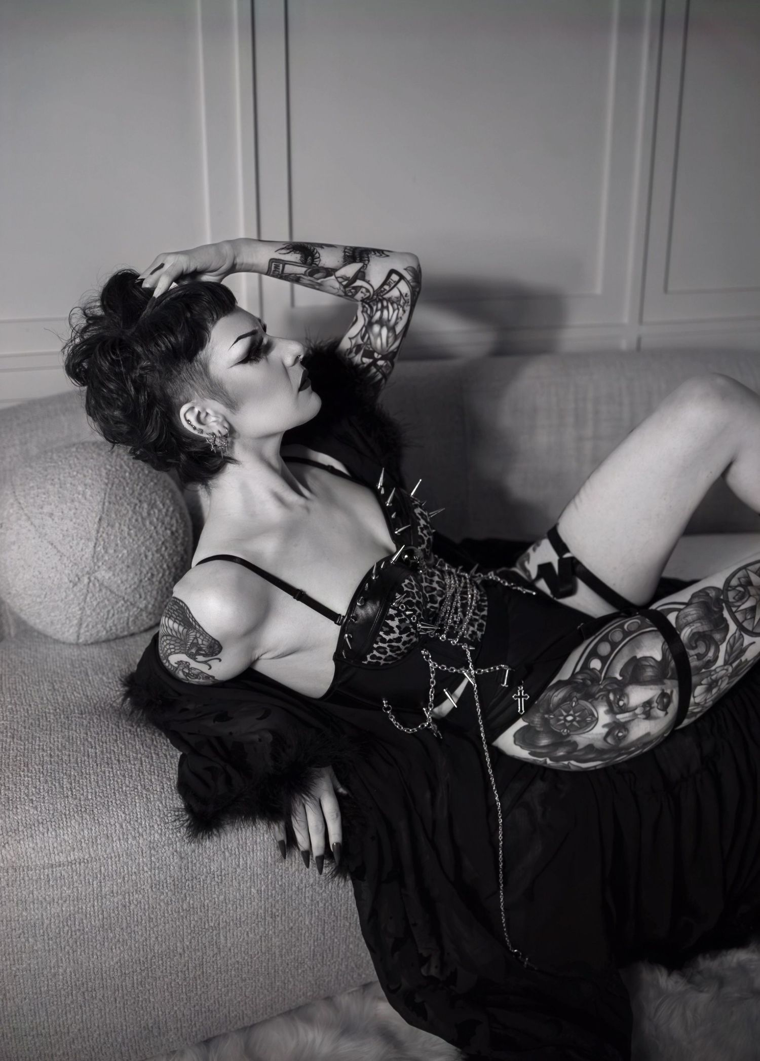 Artistic black and white boudoir photoshoot with vintage glamour styling against light colored wall.