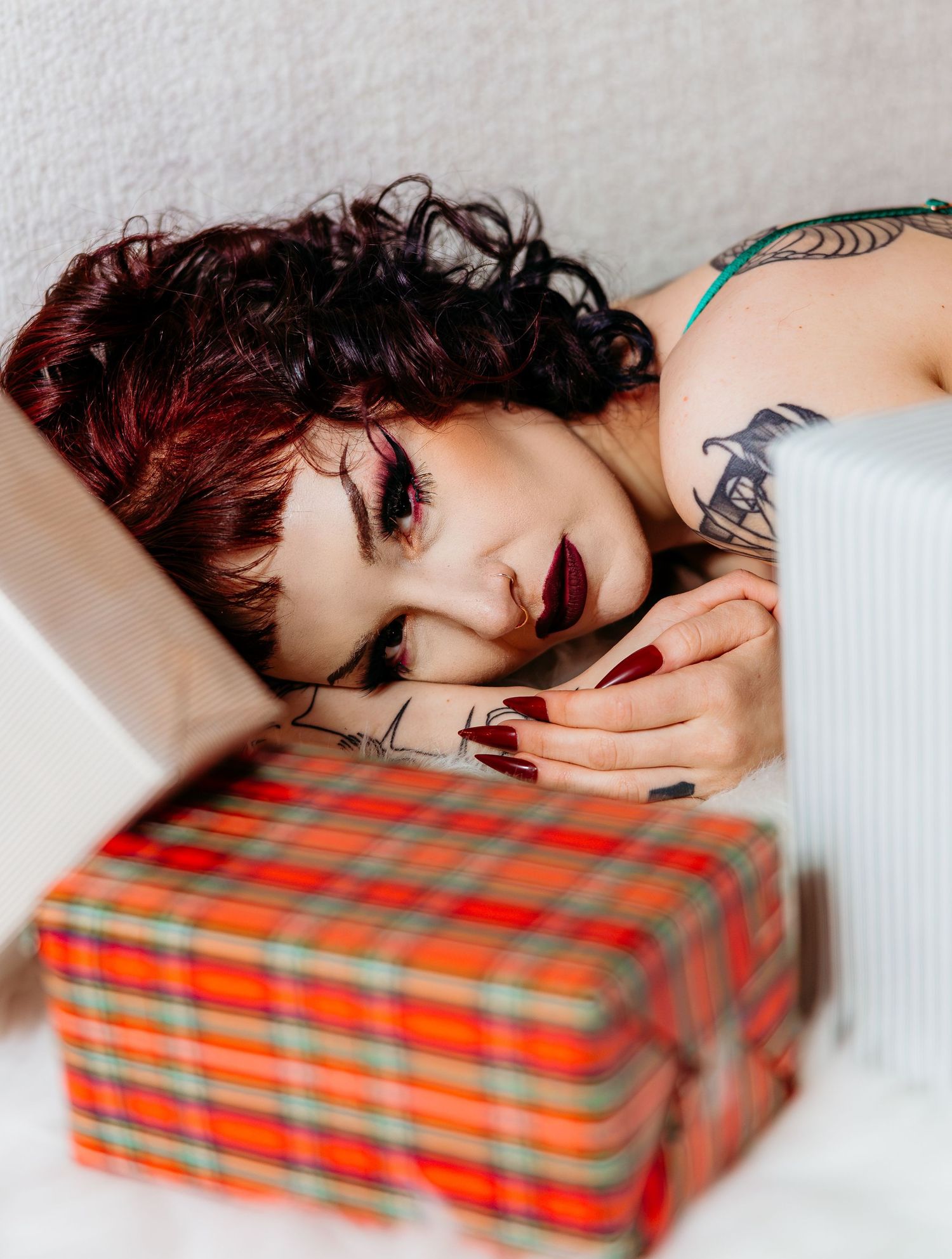 Artistic portrait depicting a person resting their head on a plaid gift box in a dreamy mood.