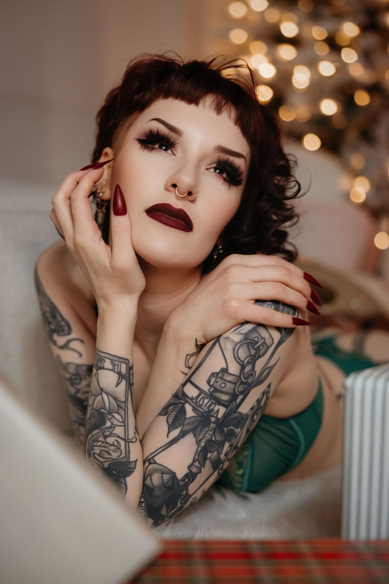 Artistic portrait series showing detailed sleeve tattoos and dark lipstick against a bokeh light background.