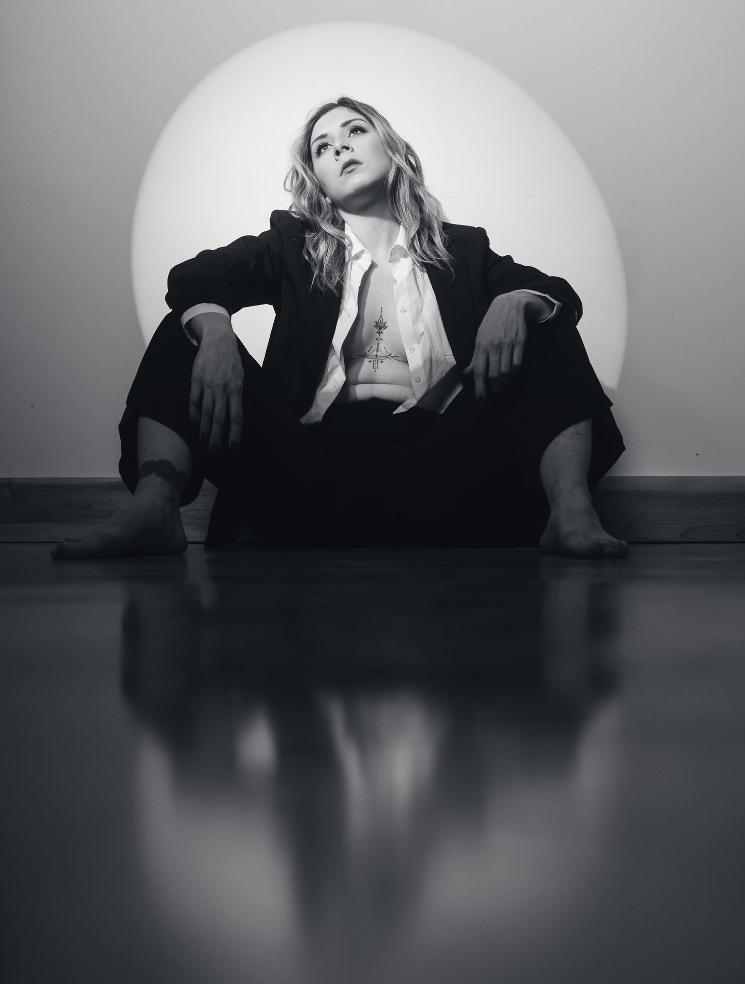 Dramatic black and white sequence of figure in dark clothing lying on reflective floor with moody lighting.