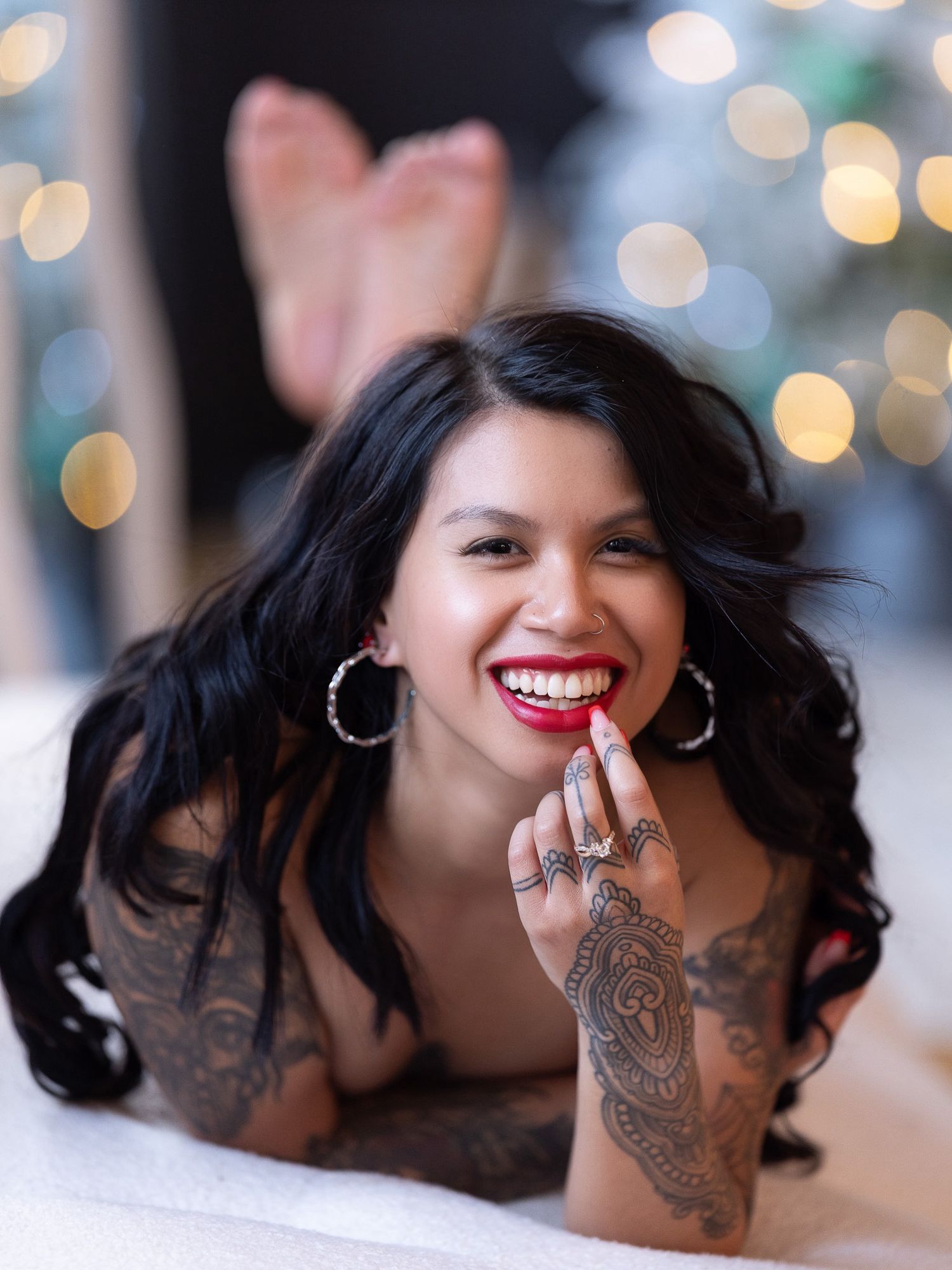 Artistic portrait with bokeh lights and decorative tattoos against a soft blurred holiday background.