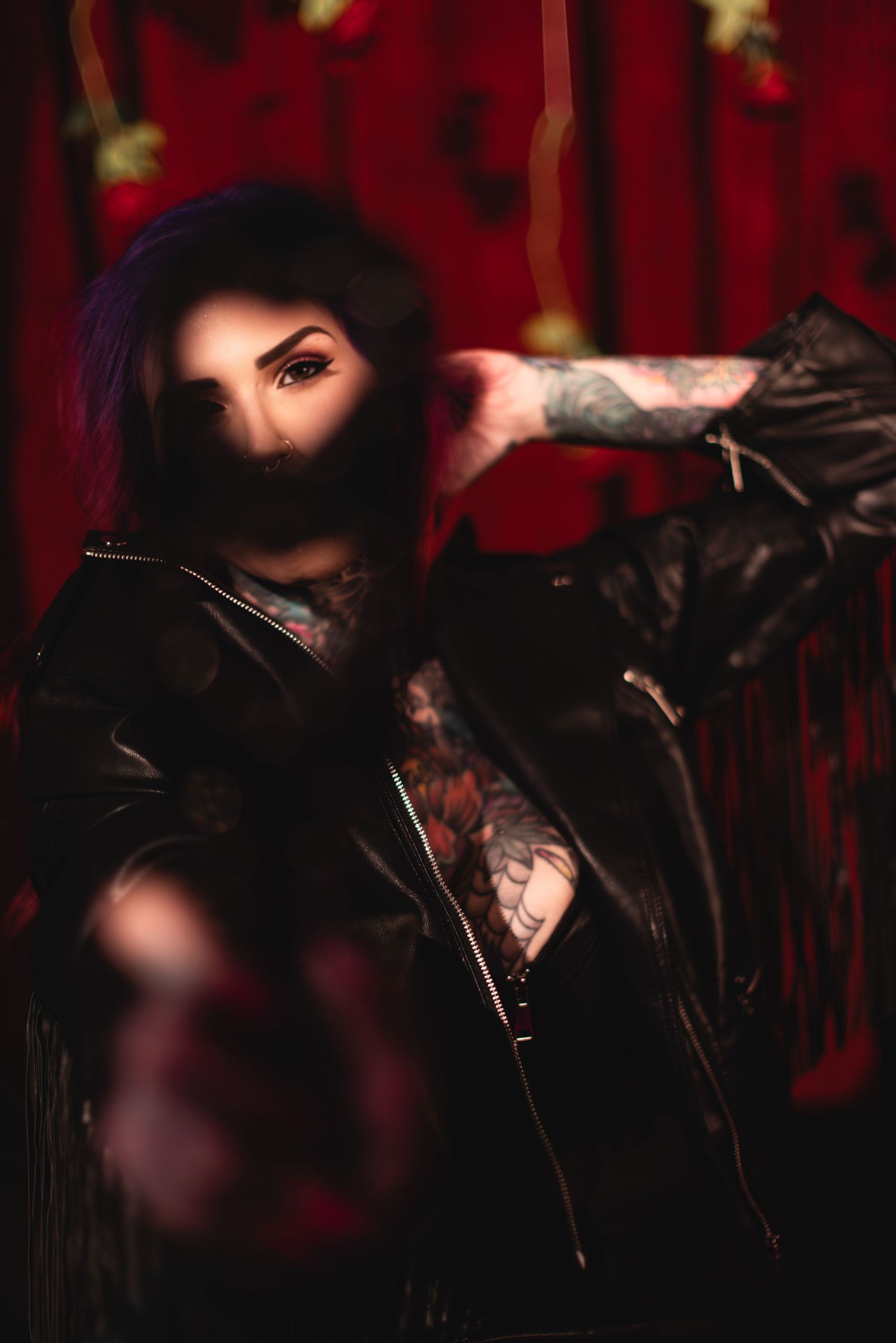 Dark moody portrait featuring bright red background and black leather jacket details.
