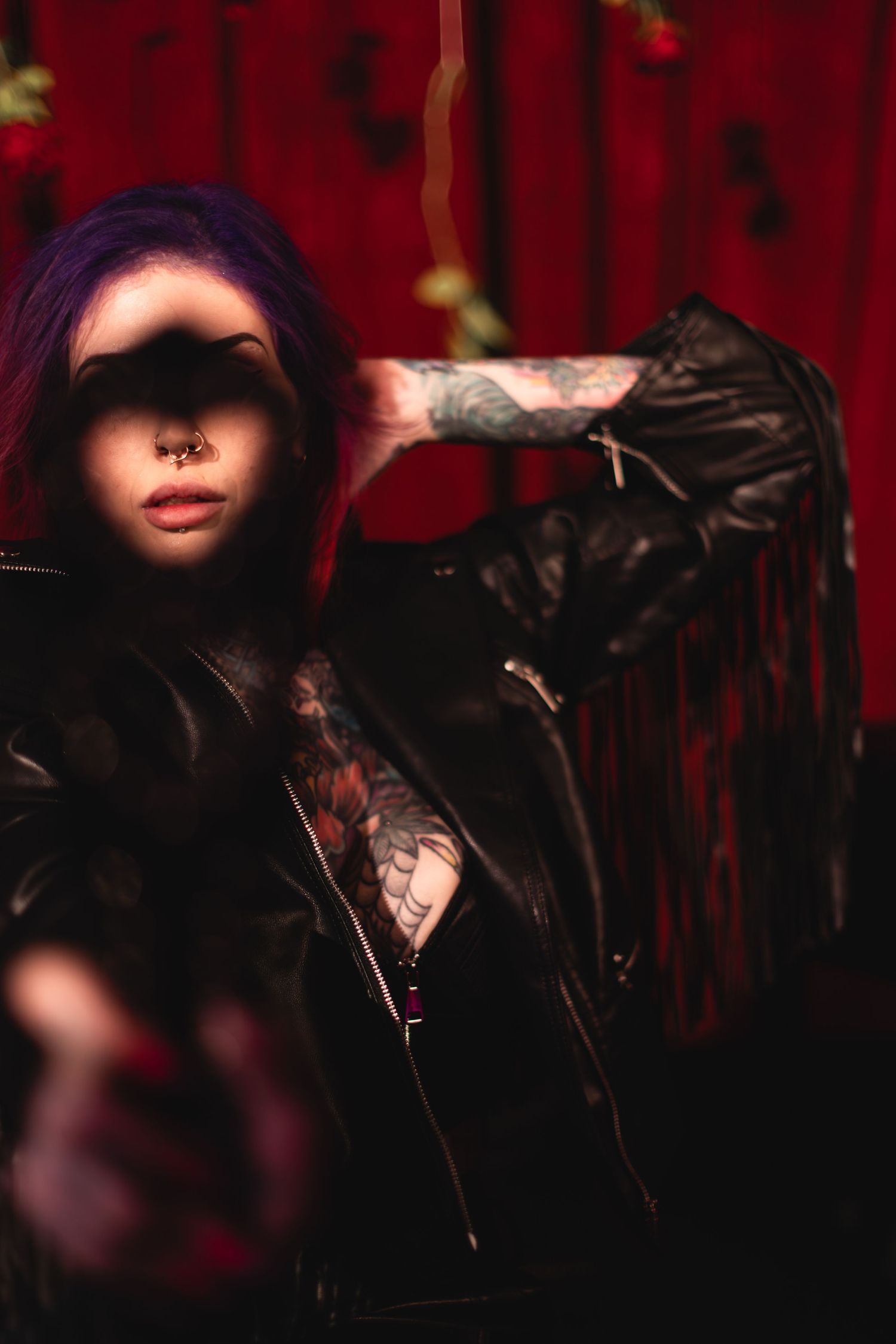 Close-up artistic shot with vibrant red lighting and septum piercing detail.