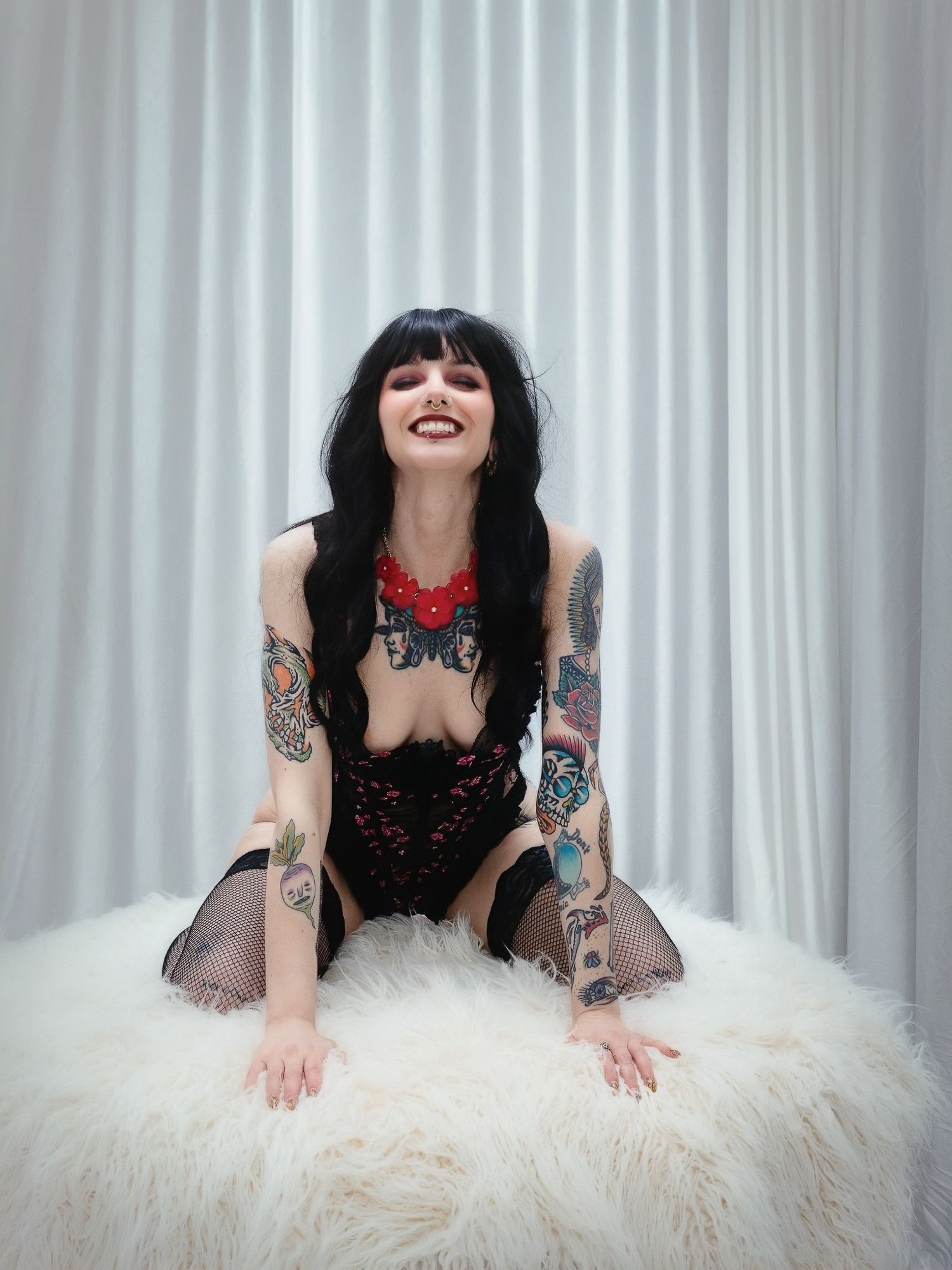 A person in black with tattoos poses playfully on a white fluffy rug in a series of four artistic shots.