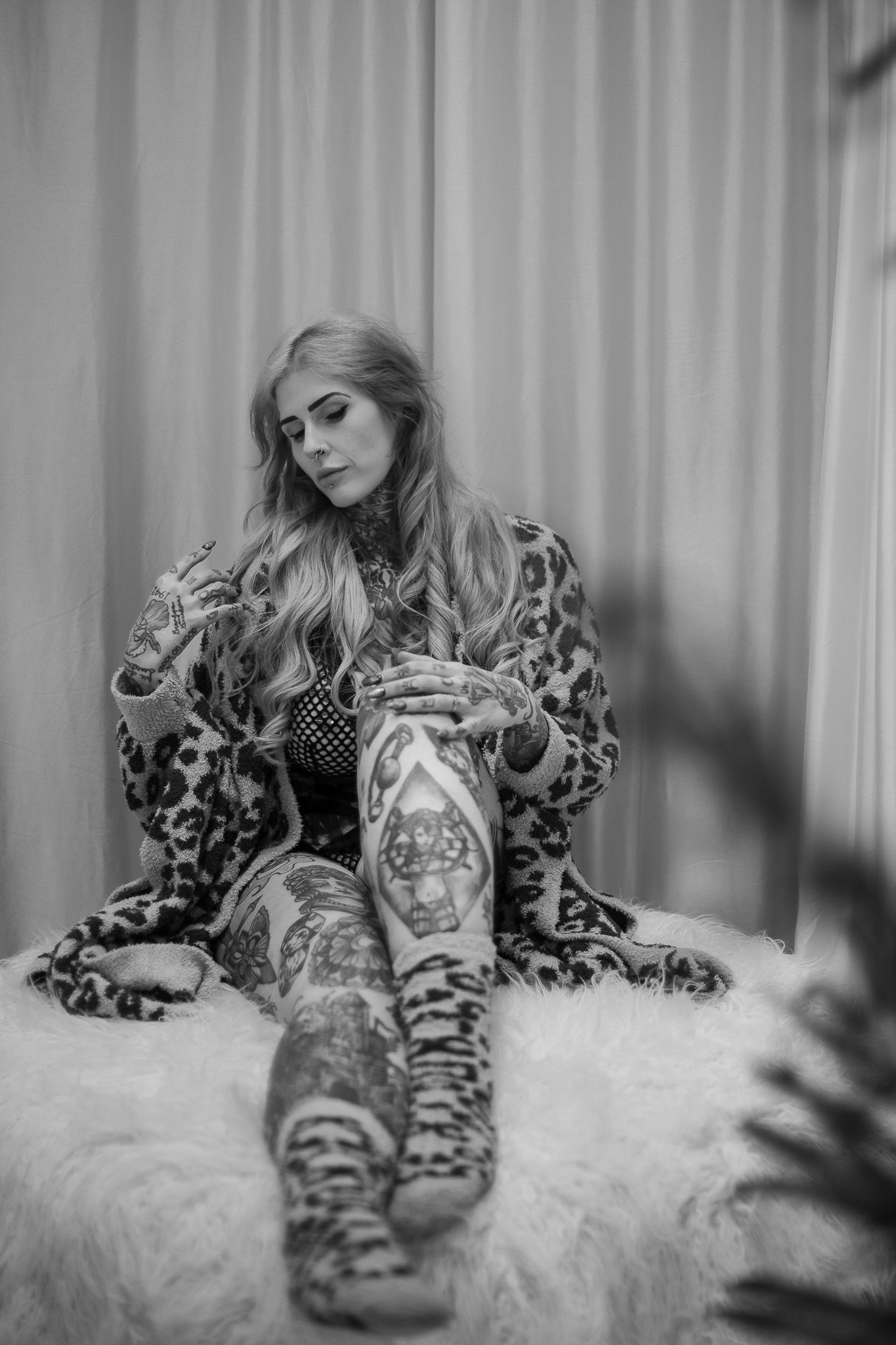 A person in leopard print boots lies on a white fur rug in a black and white photo series.