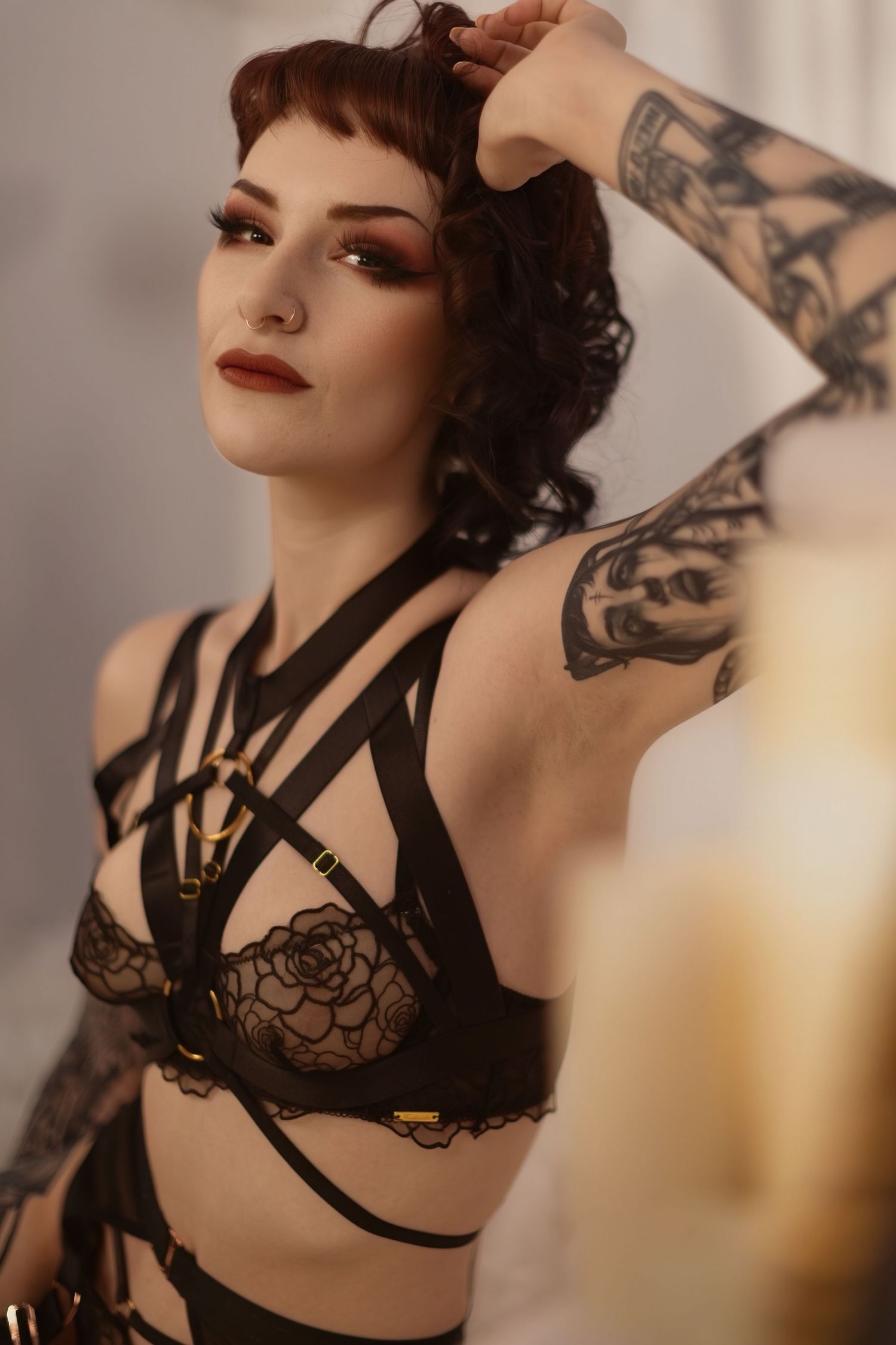 Artistic boudoir photoshoot featuring dark lingerie with strappy details in moody atmospheric lighting.