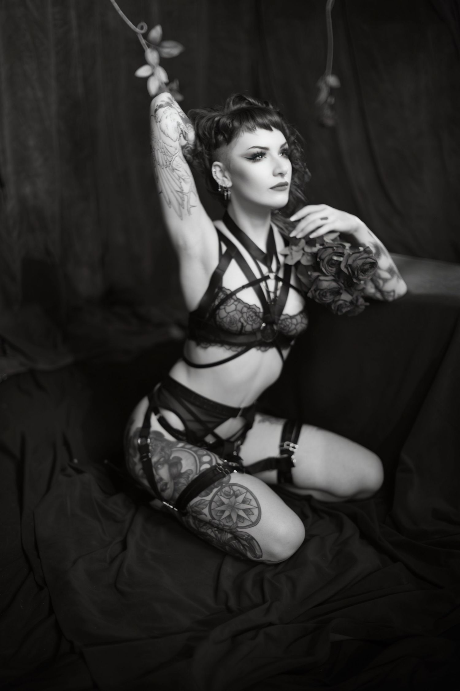 A series of black and white vintage style boudoir portraits with dramatic lighting showing poses against a dark background.