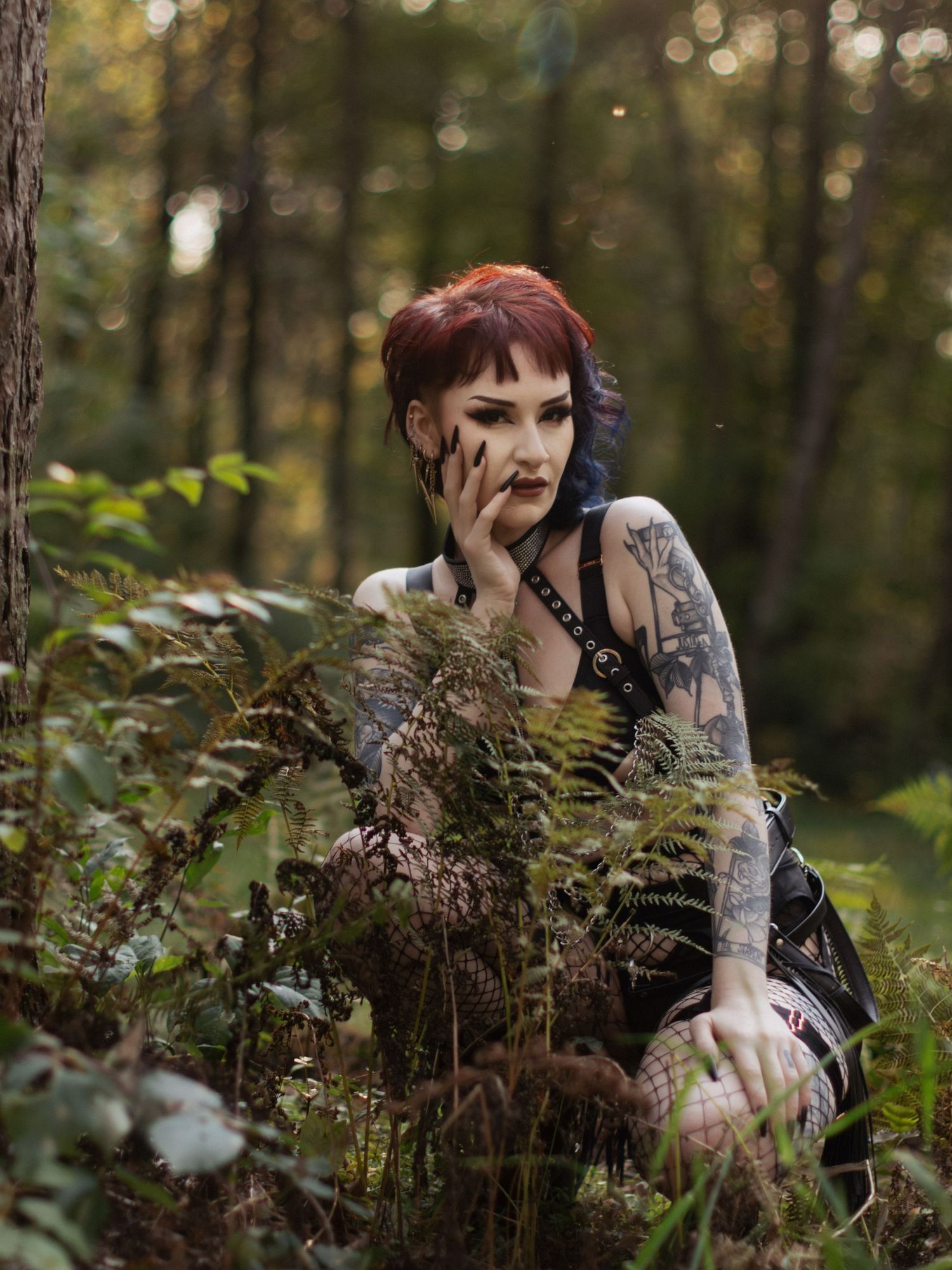 Artistic forest portrait with model partially hidden behind autumn foliage.