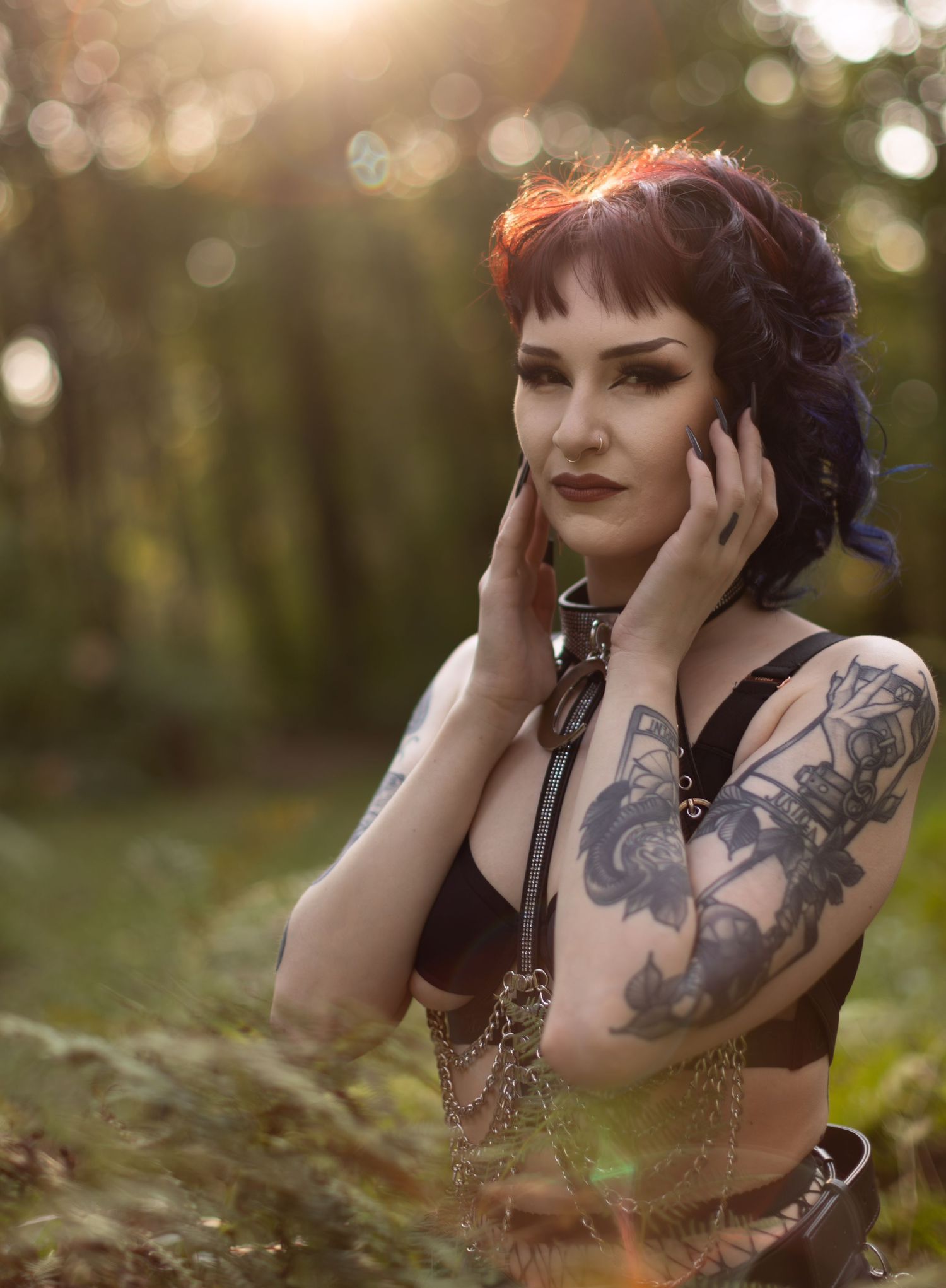 Artistic portrait in forest with bokeh lighting and gothic fashion elements.