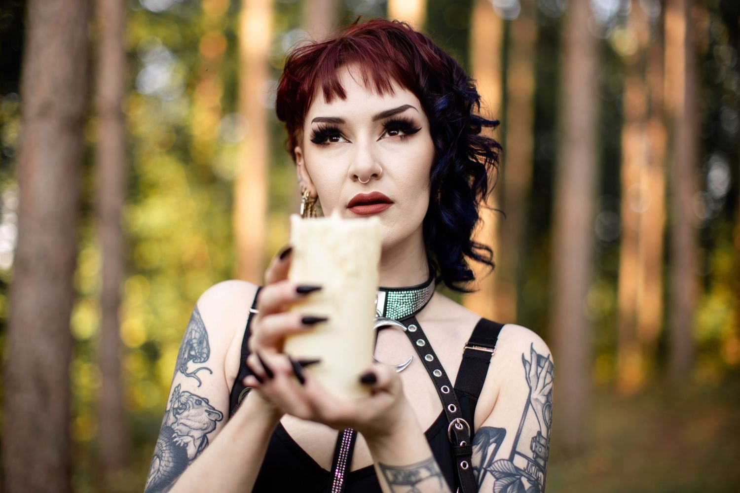 Alternative model with tattoos poses in a forest wearing gothic fashion and fishnet stockings.