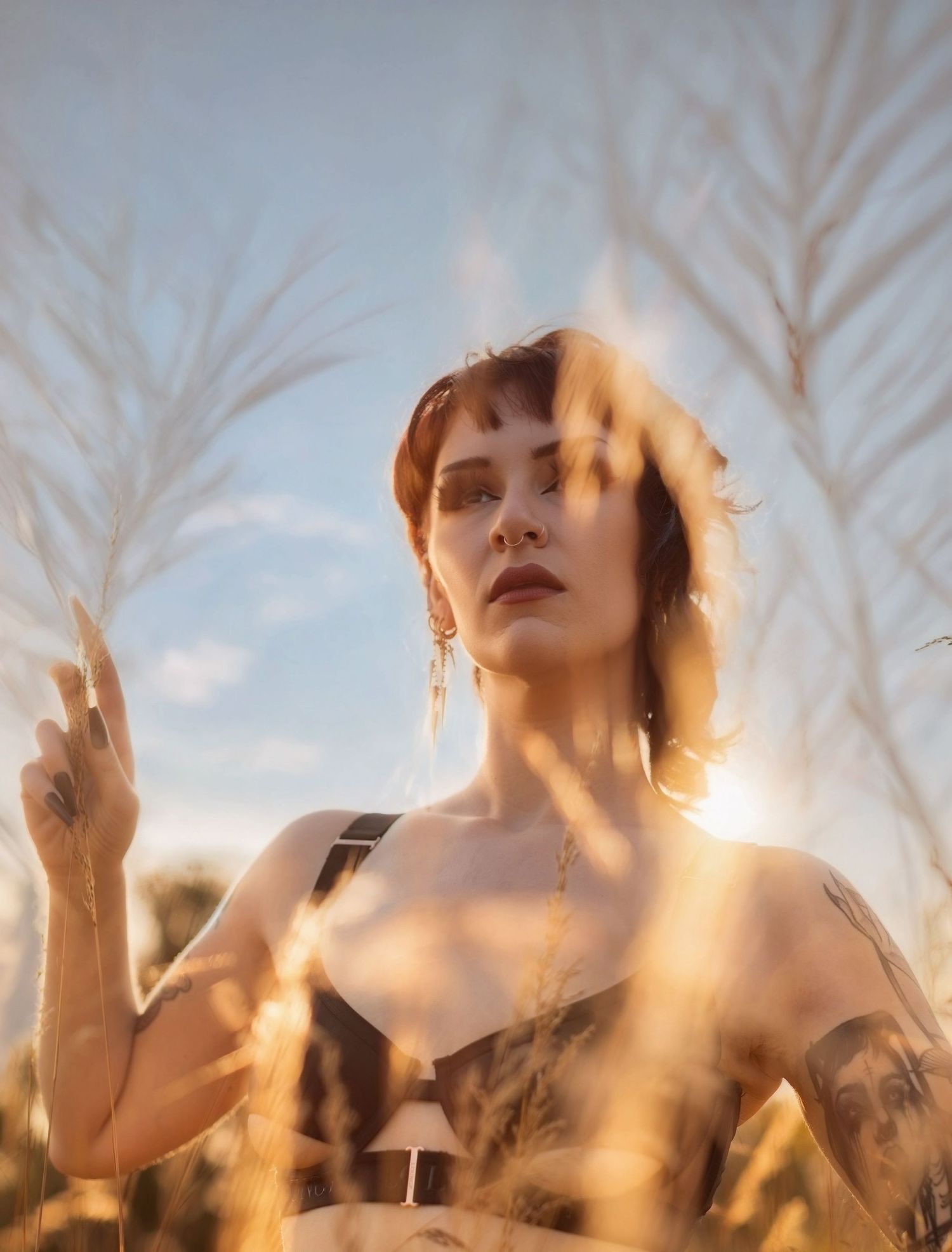 Artistic portrait in wheat field with sunlight creating dramatic shadows and highlights.