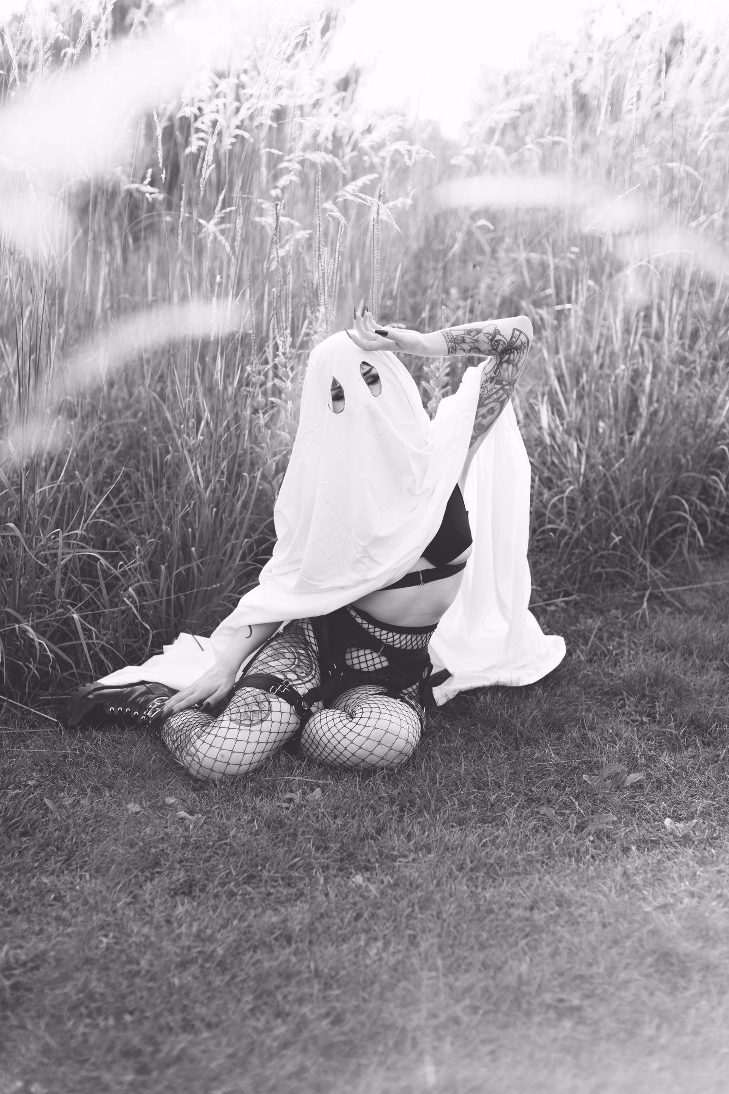Artistic black and white photo of ghost costume in tall grass field.