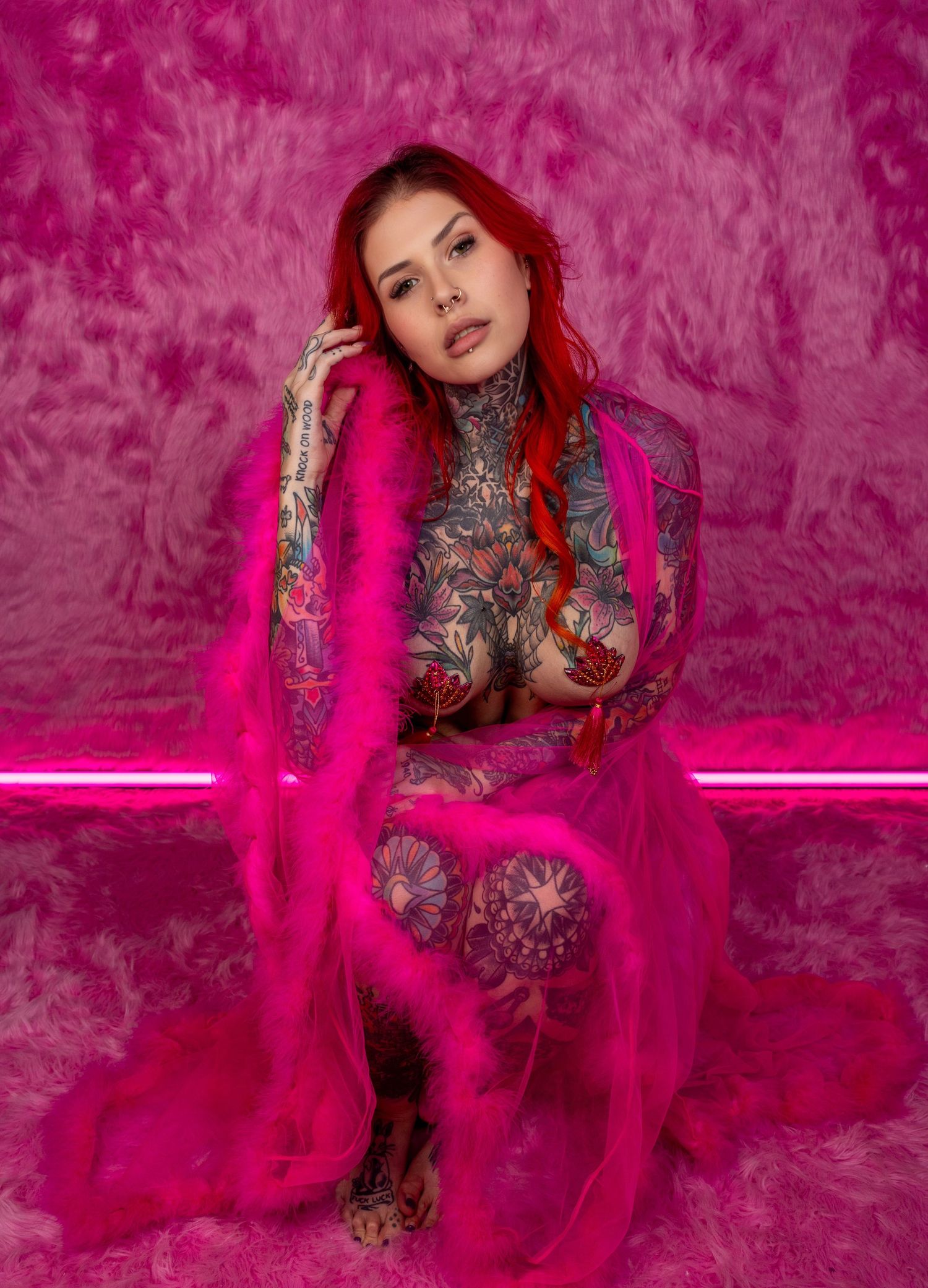 Fashion model in bright fuchsia tulle gown poses against vibrant pink backdrop with dramatic lighting effects.