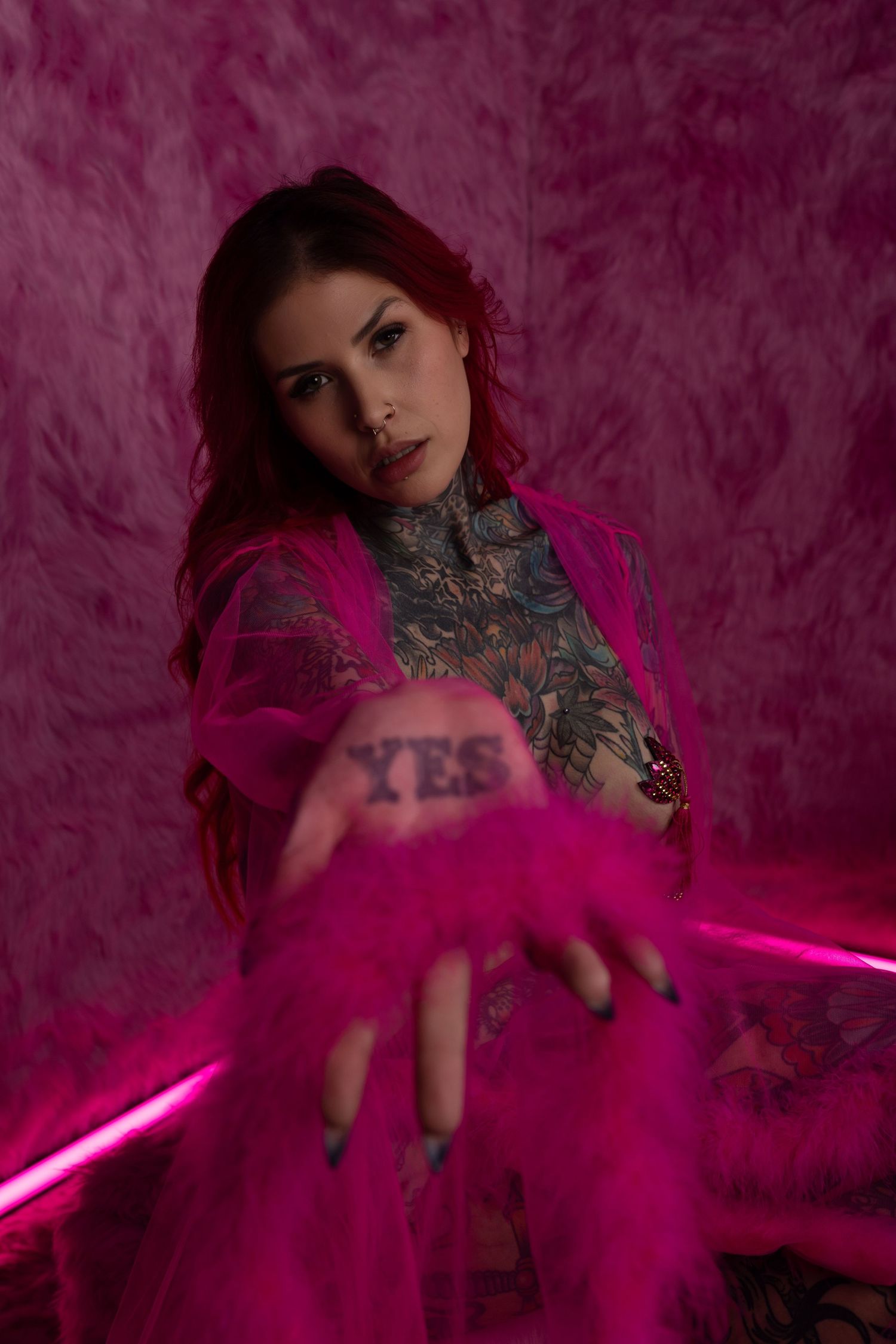 Artistic portrait with pink smoke effects and neon lights creating a dramatic ethereal atmosphere against dark background.