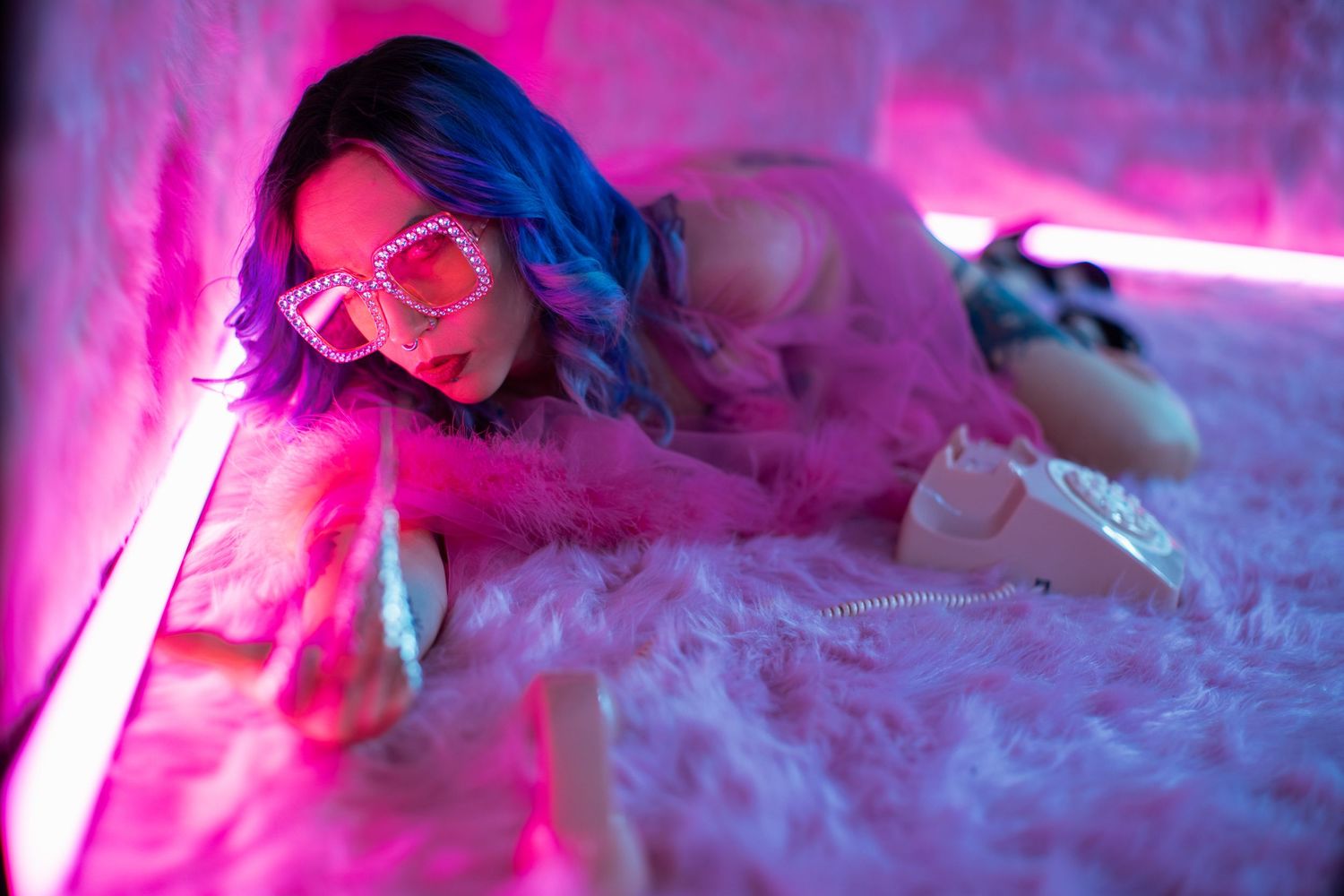 Pink neon lights illuminate tall frosted cocktails with colorful garnishes lined up at a bar.