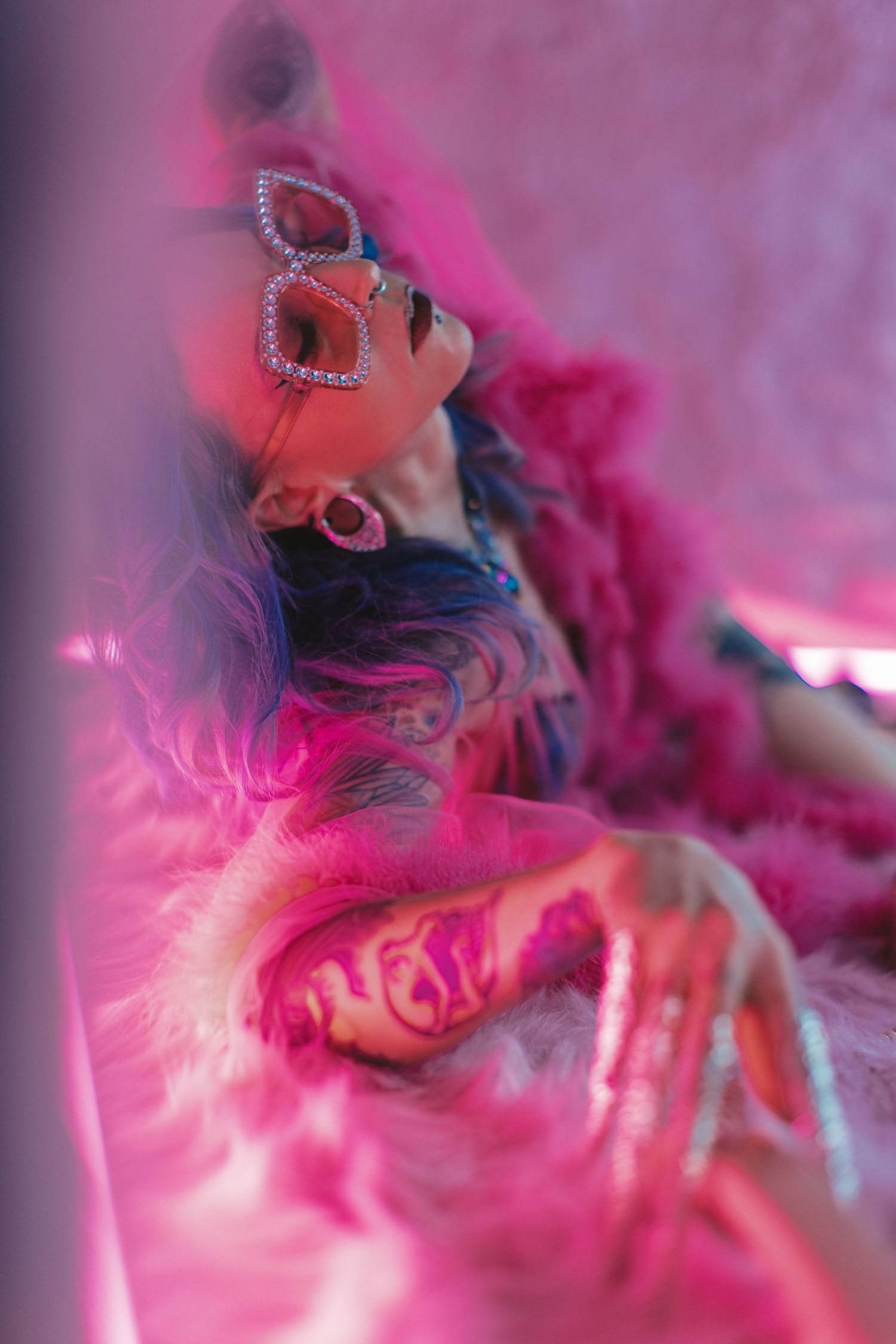 An artistic macro photograph shows pink and white feathers in soft focus creating a dreamy, ethereal texture.