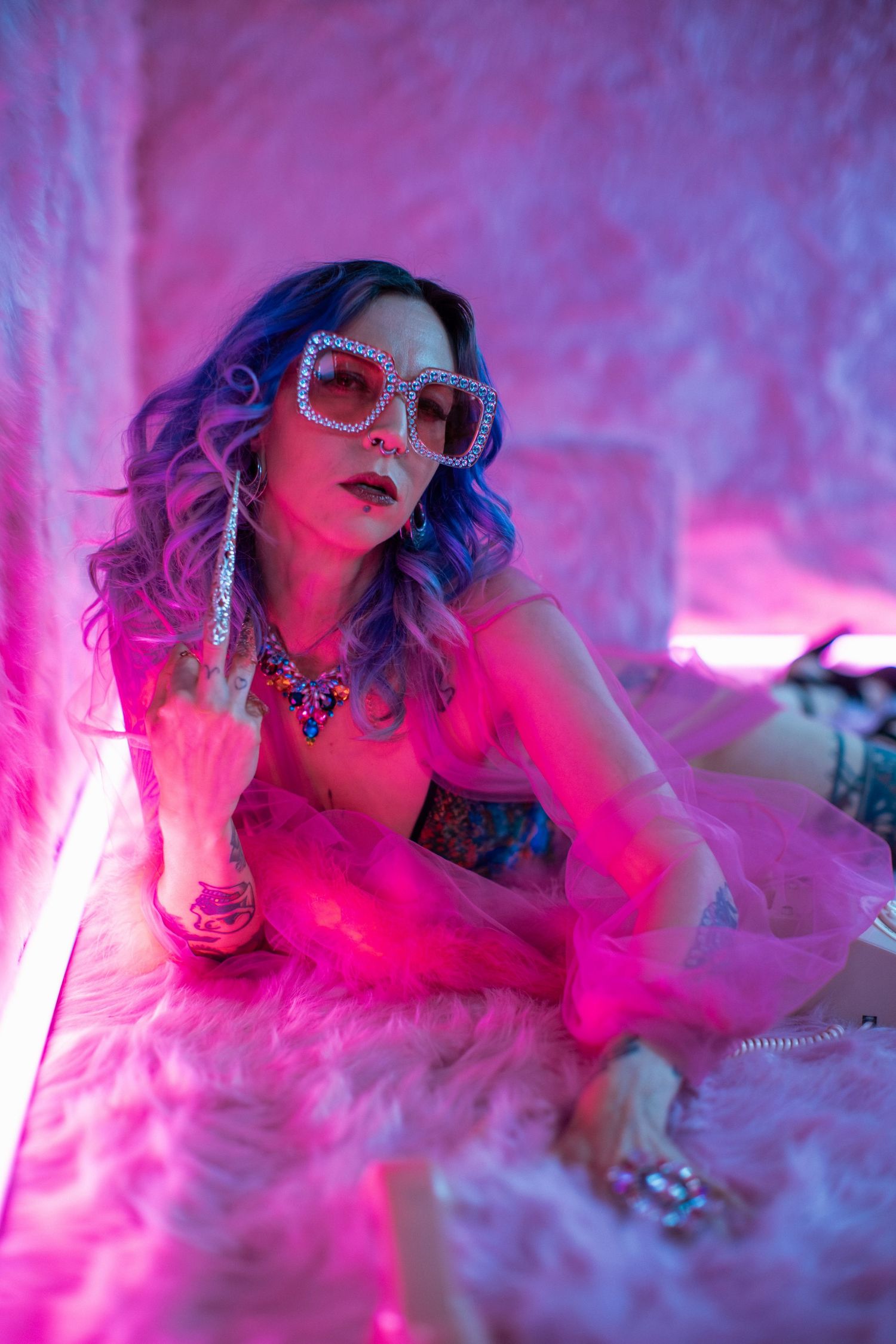 A creative fashion portrait with pink lighting features sunglasses and smoke effects creating a dreamy ethereal mood.