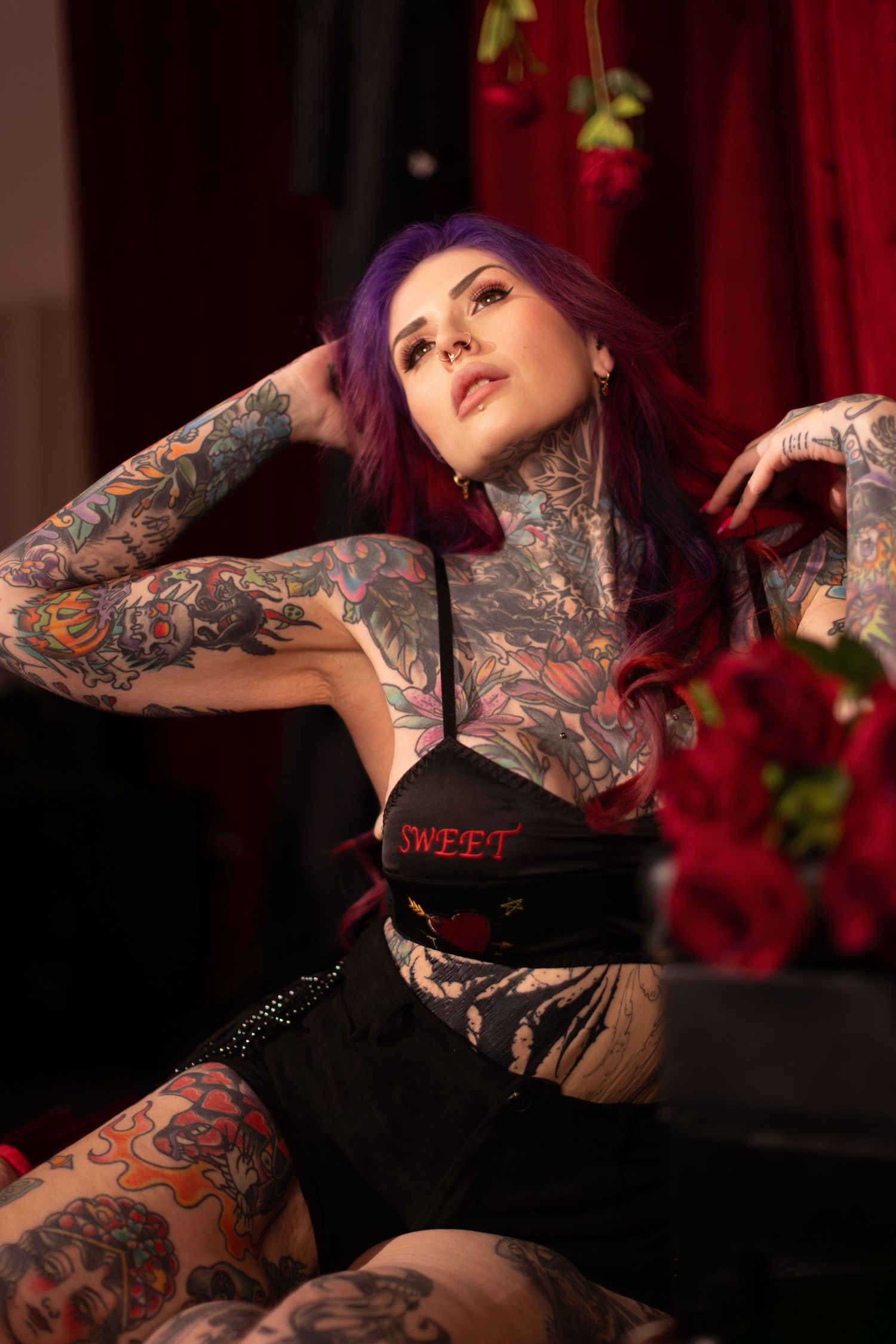 Artistic boudoir photoshoot featuring intricate tattoo artwork in dramatic red and black lighting.