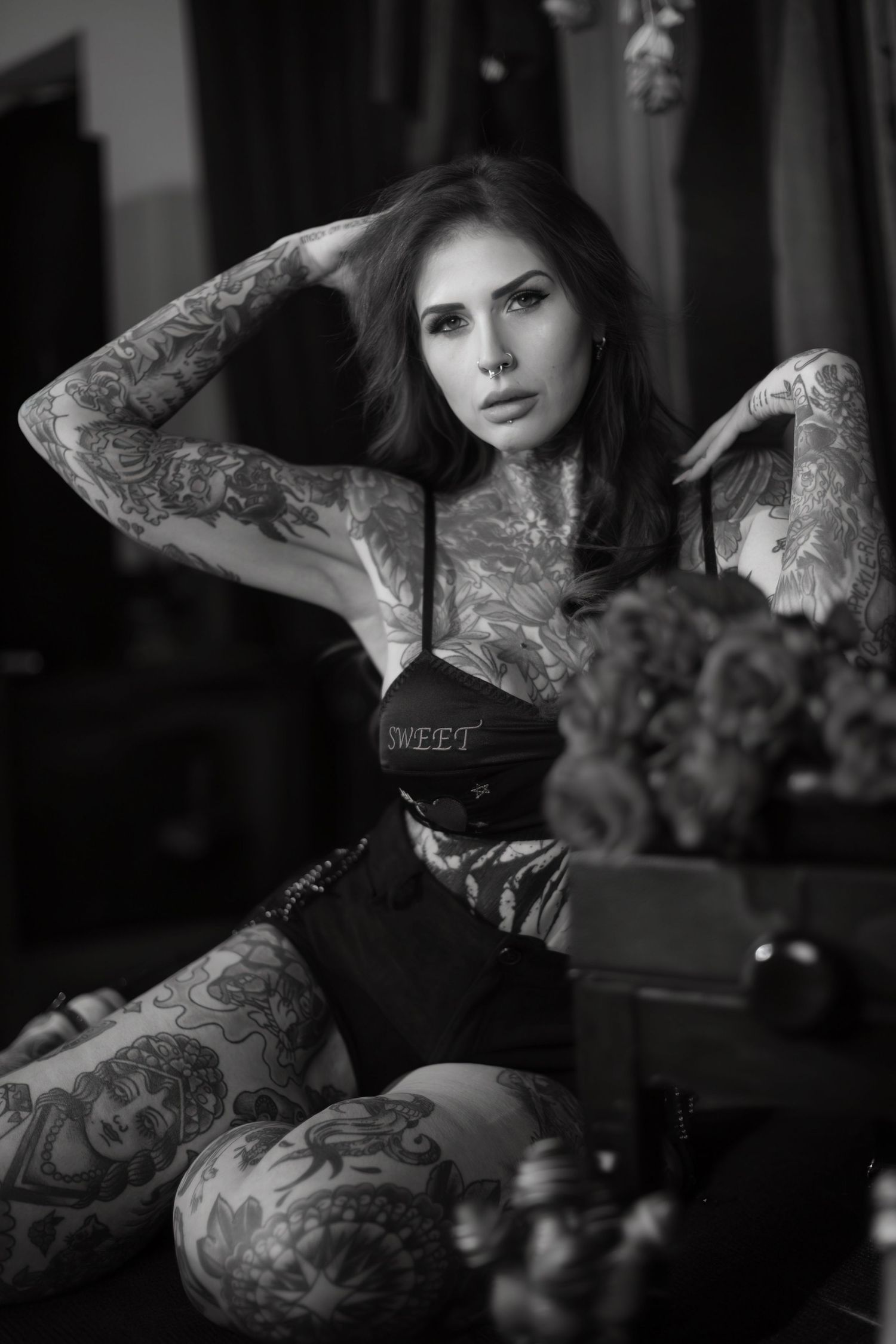 A woman in dark gothic attire poses and shows off intricate tattoo artwork in a dark moody photo sequence.