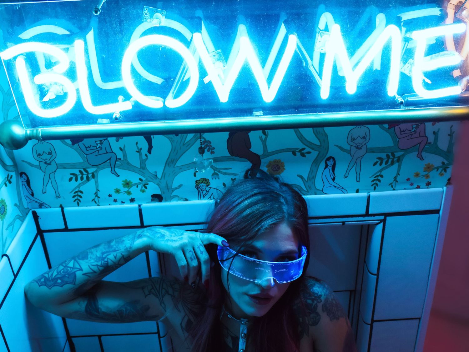 Neon blue lighting illuminates graffiti text on a dark wall.