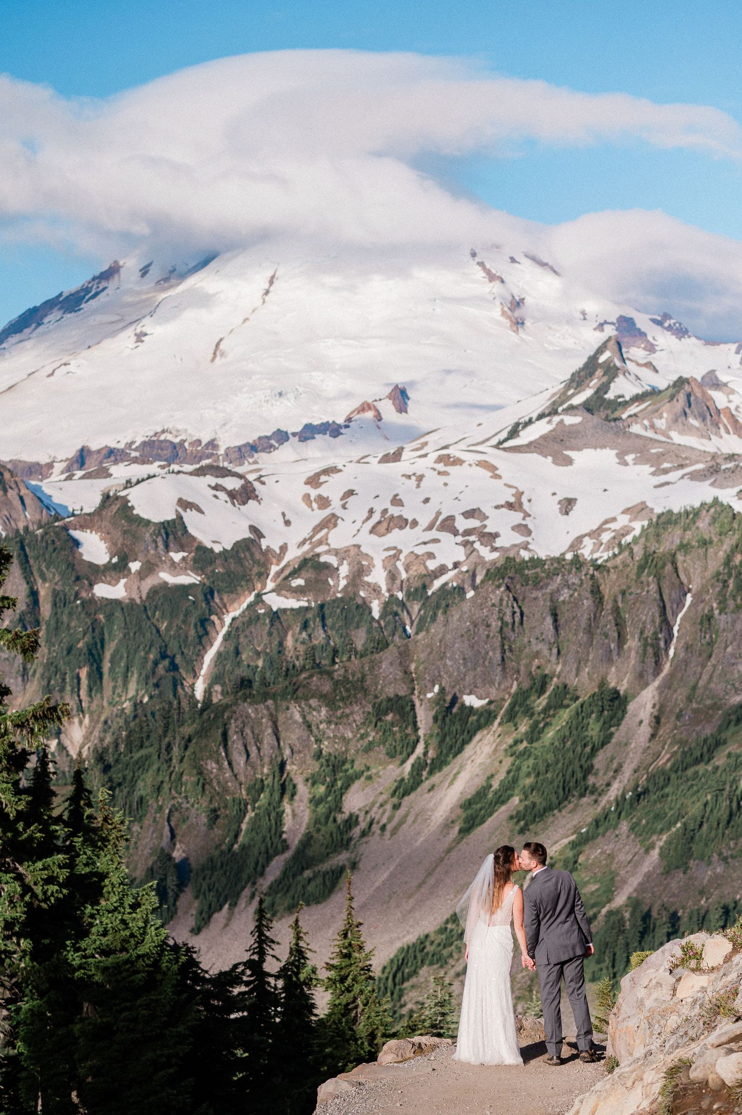 bride and groom kissing on a sunny day with Mt. Baker in the background