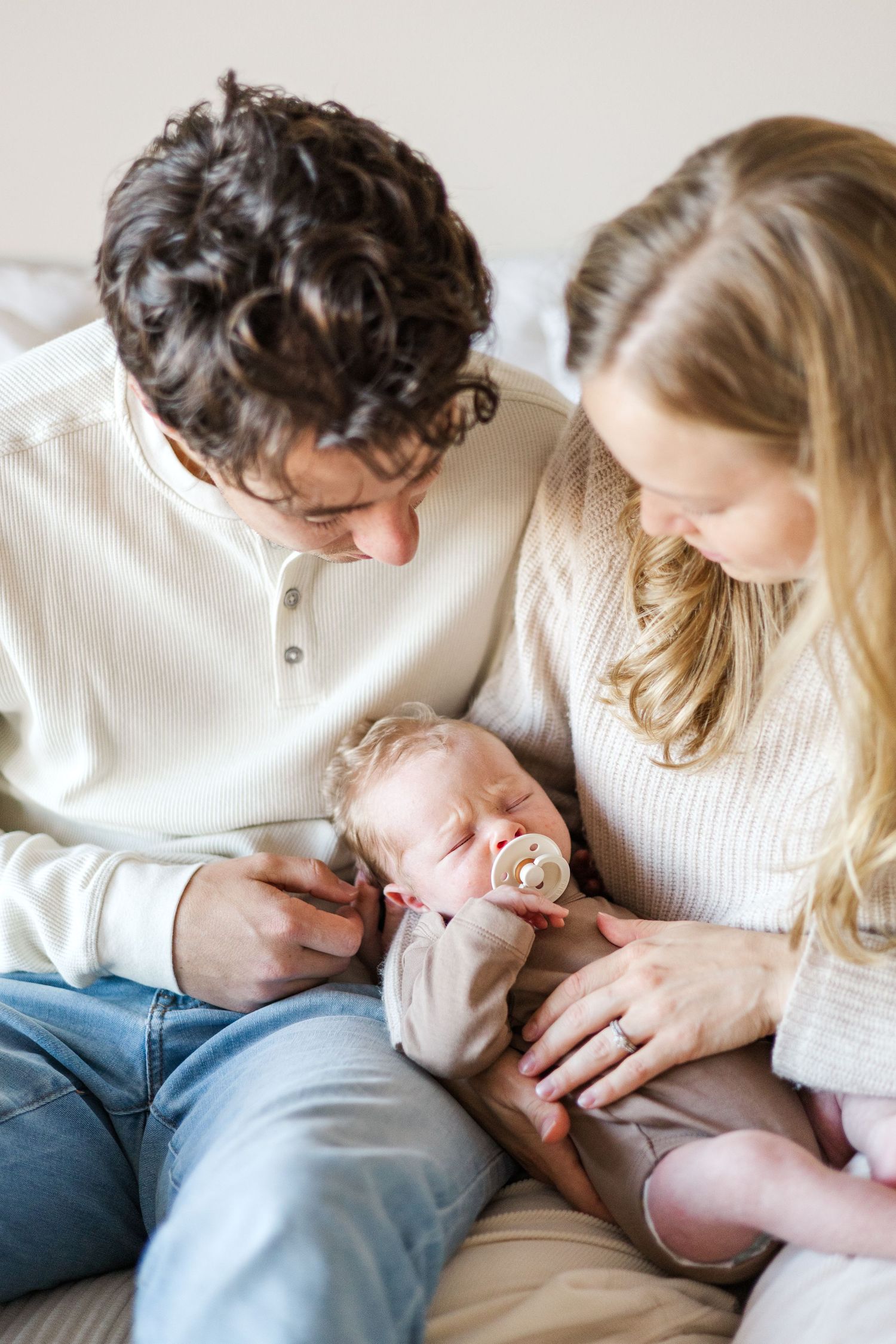 Couple sharing tender moments with their newborn baby in casual home setting.