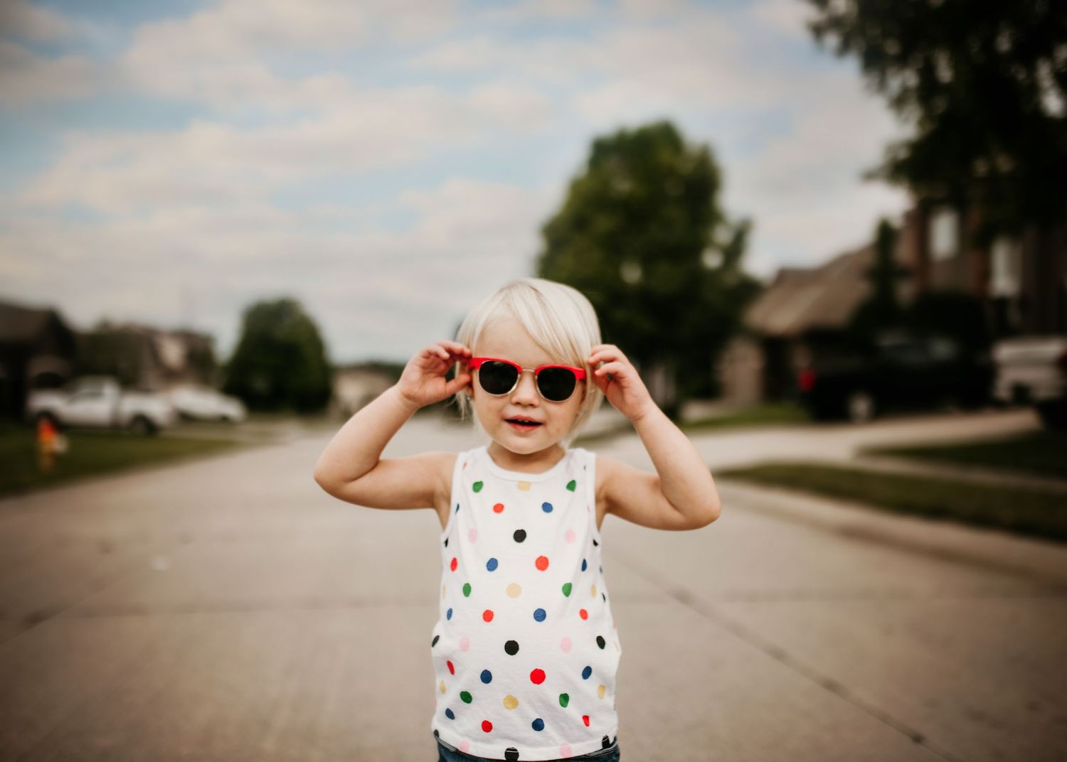 Child in her neighborhood during the summers putting on her sunglasses