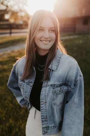Portrait against sunset with person wearing denim jacket and black top.