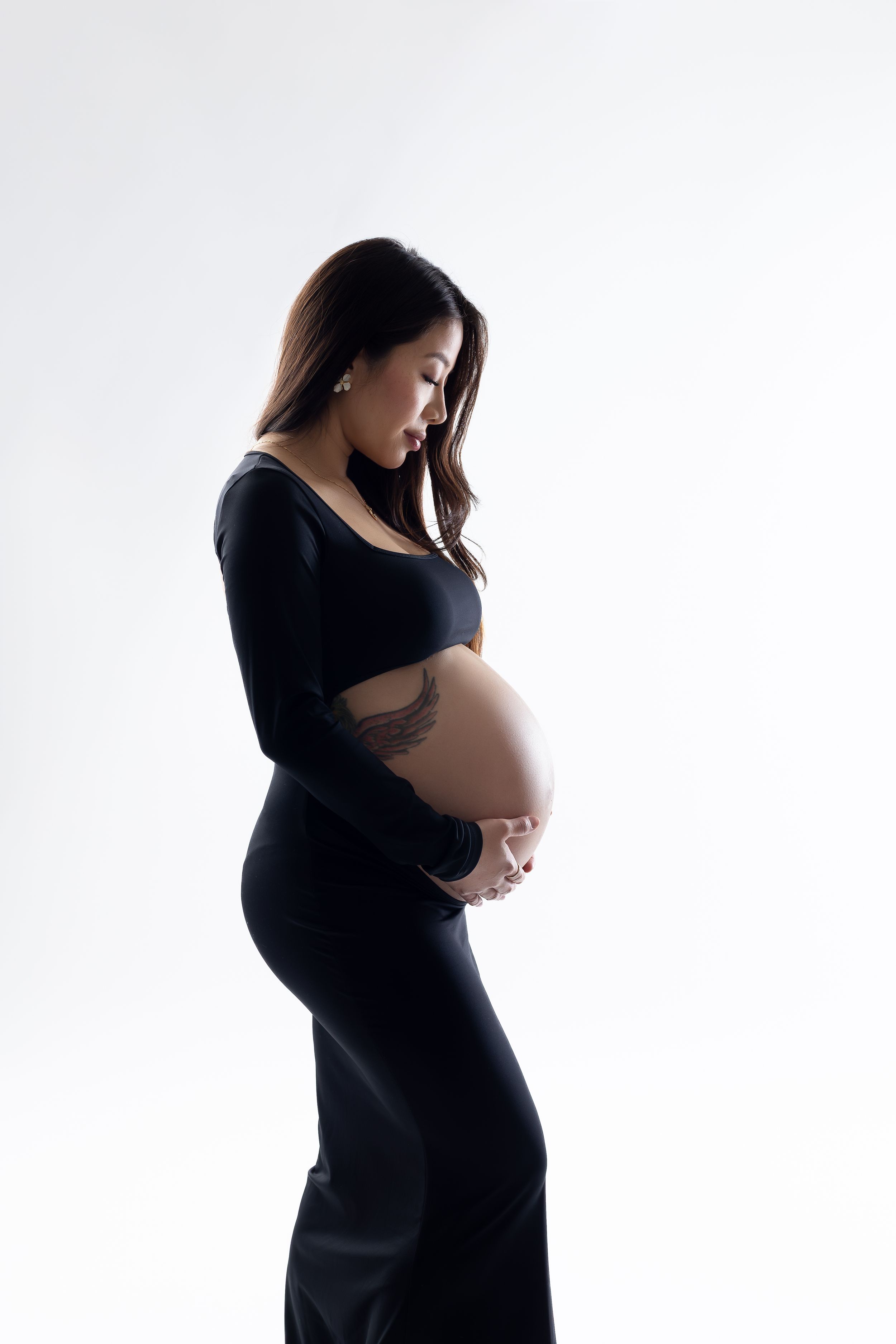 Silhouette of pregnant woman in black dress shown in four artistic profile poses against white background.