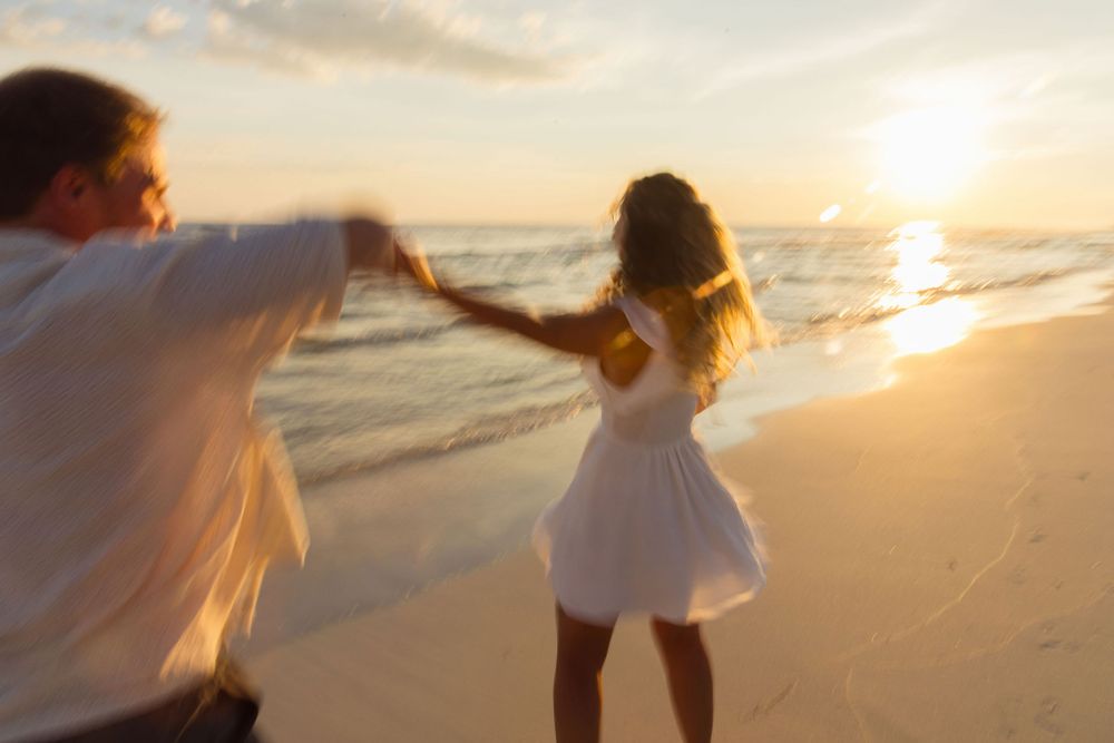 Couple dancing together on beach at golden sunset.