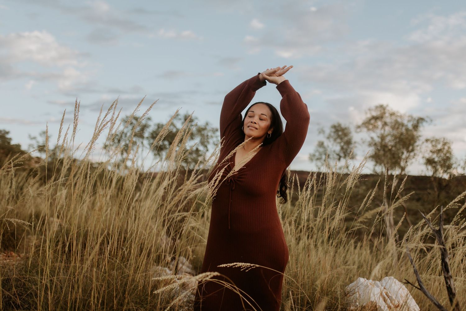 Woman standing on rocks posing while looking over her shoulder at Lake Moondarra, Mount Isa