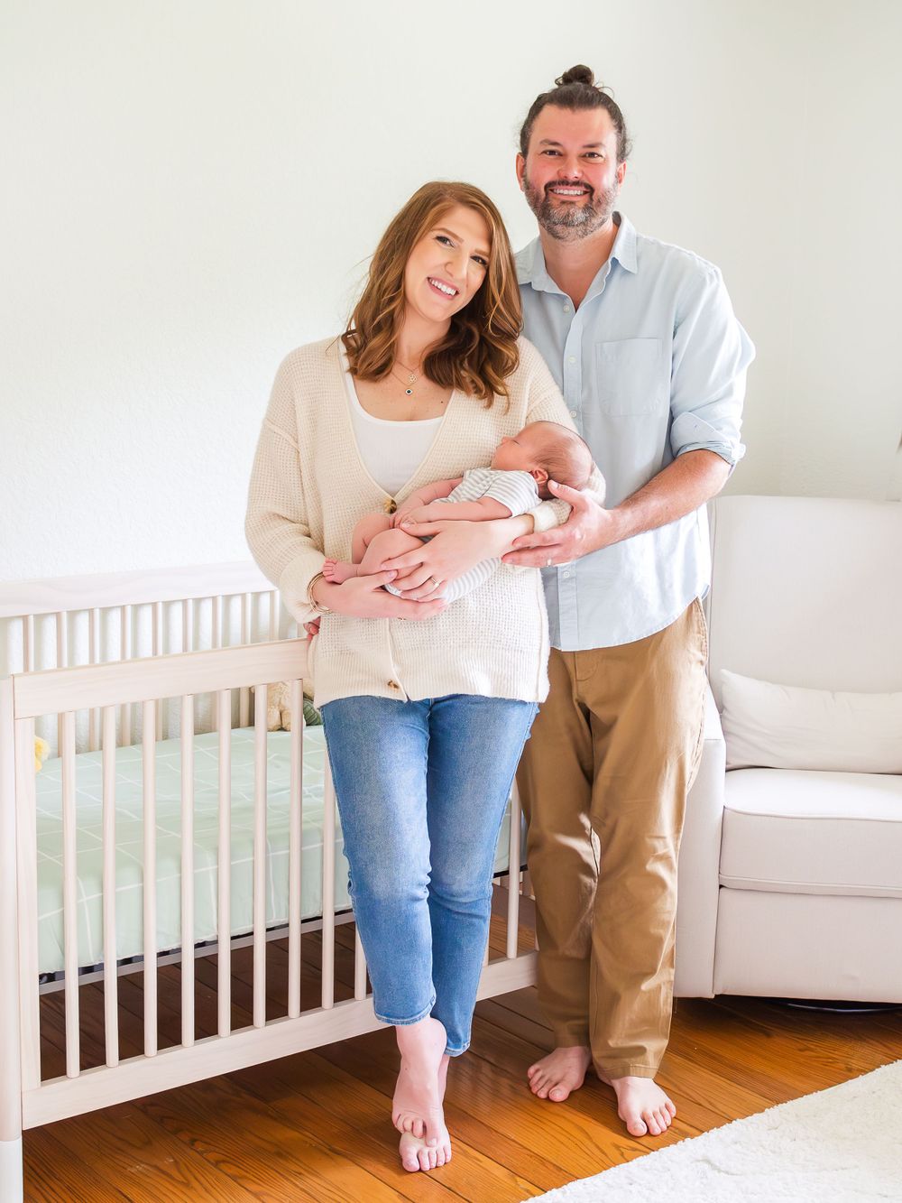 parents holding newborn baby near crib in decorated nusery. in-home newborn session in sonoma County .