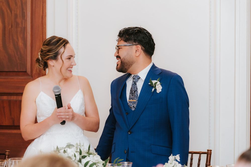 A couple in wedding attire share an intimate moment during their reception at an elegant indoor venue.