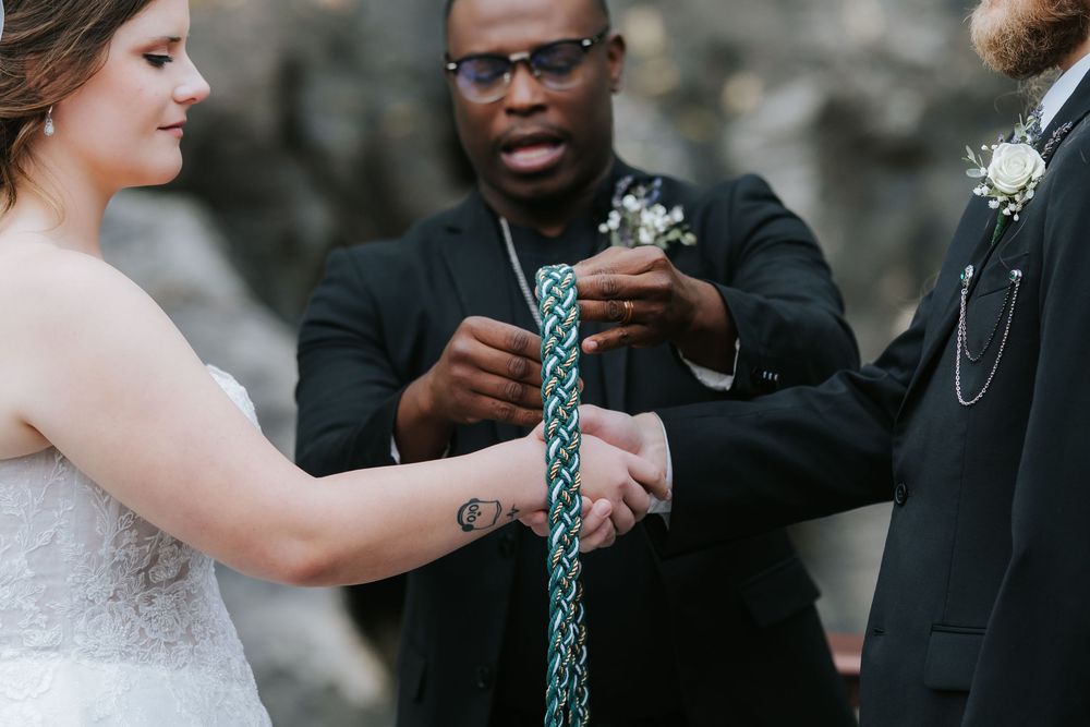 A couple participates in a handfasting ceremony with braided cord during their wedding ceremony.