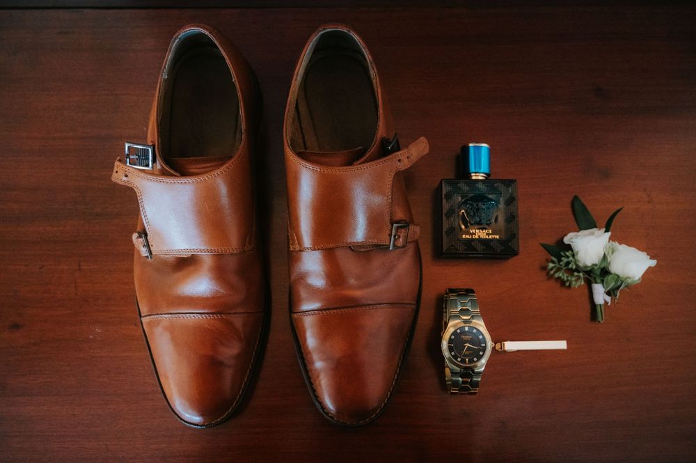 Brown leather dress shoes displayed with accessories on a dark wooden surface in different compositions.