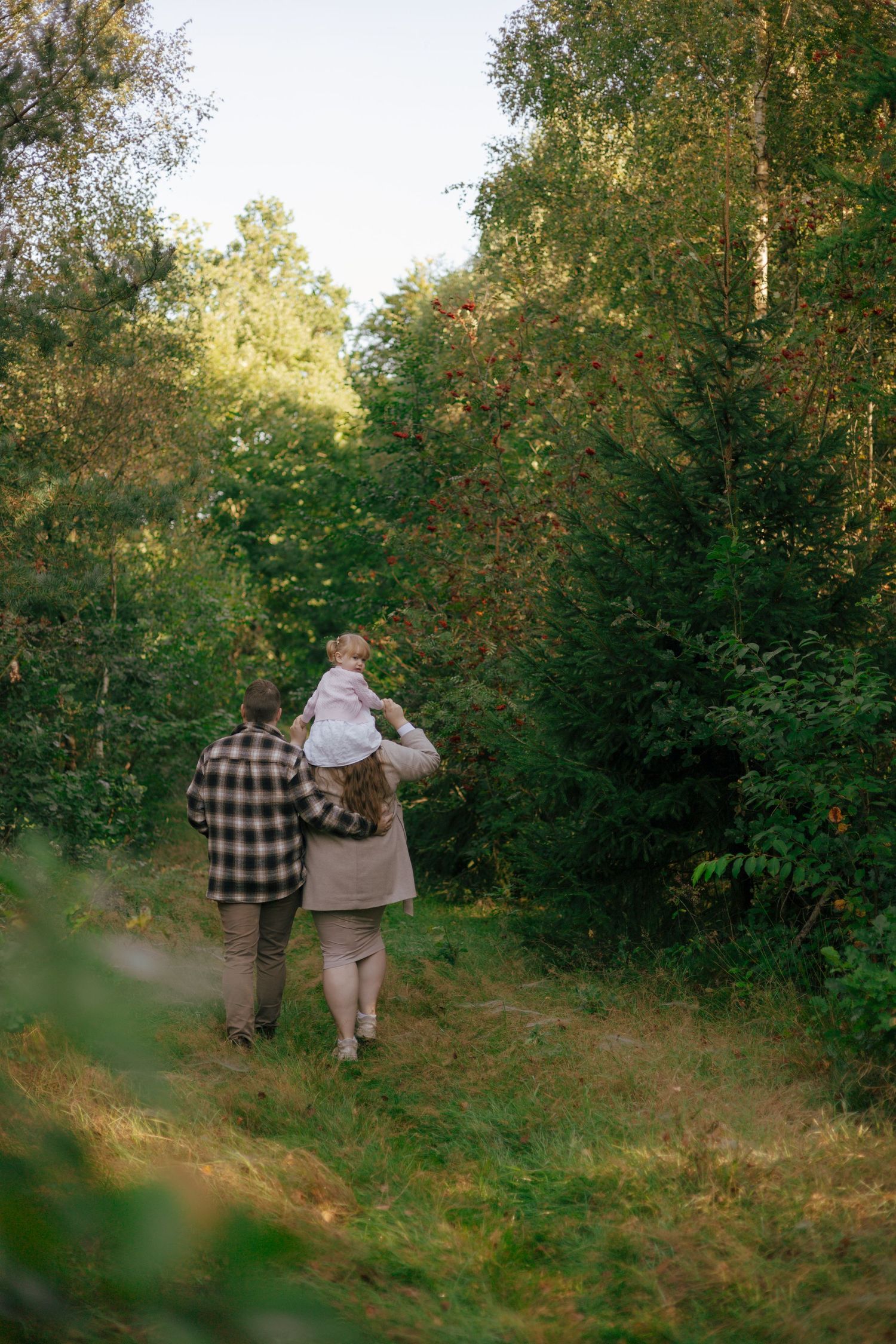 A family walking together on a forest trail during golden hour.