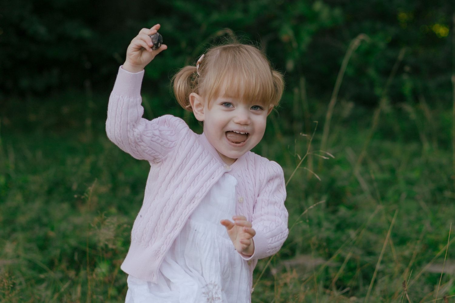A joyful child in pink clothing dancing and playing outdoors.