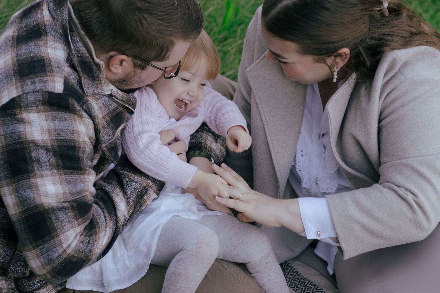 Family sitting together in nature and playing with a small child.