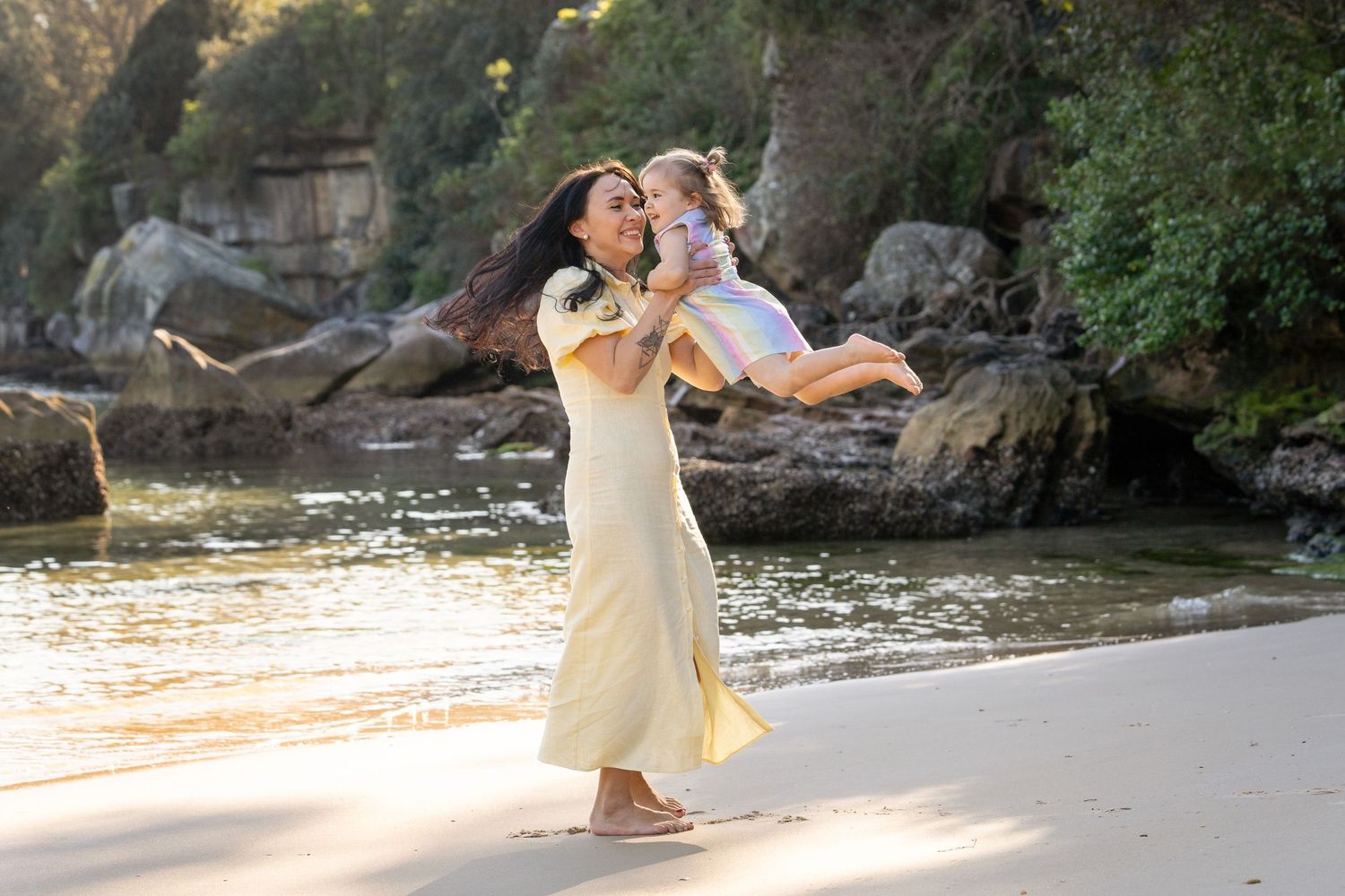 Happy mom and daughter spinning around playfully during a family photoshoot at Manly