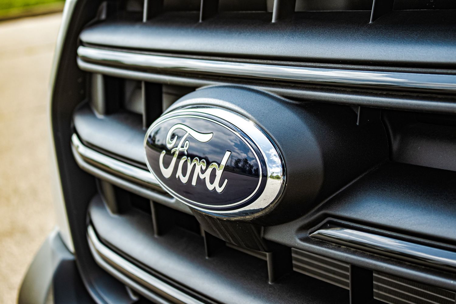 Close-up macro shot of a chrome Ford logo on a black vehicle grille.