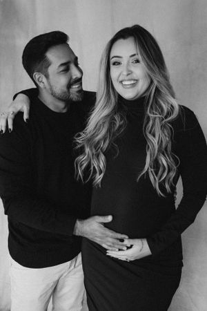 Black and white maternity portrait of couple in matching black sweaters.