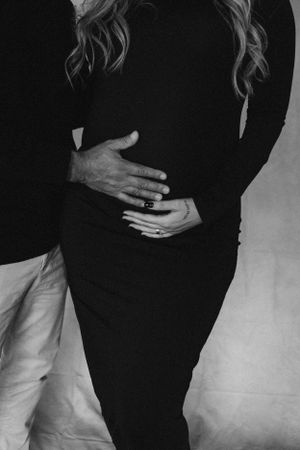 Intimate black and white maternity photo showing hands cradling baby bump.