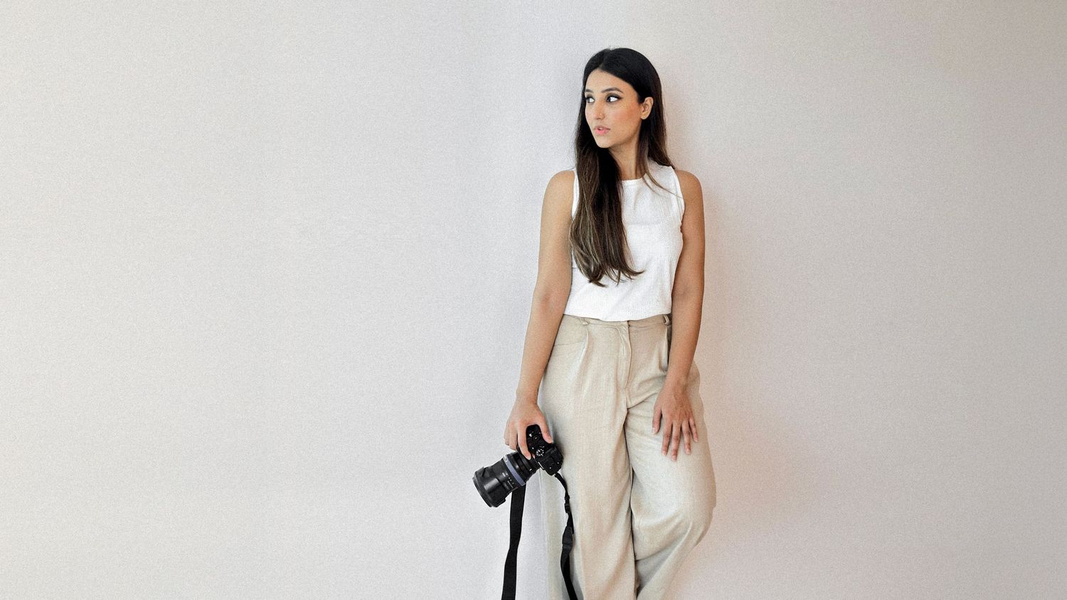 Professional portrait of Zahra Ali, Dubai photographer, holding camera in minimalist studio