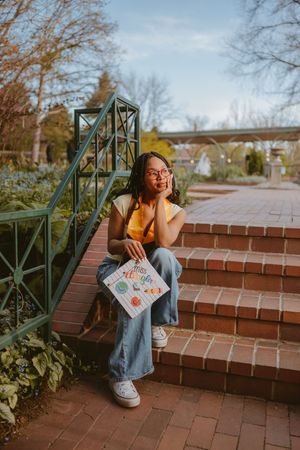 A casual outdoor photo shoot featuring denim overalls and a yellow beanie on brick steps.